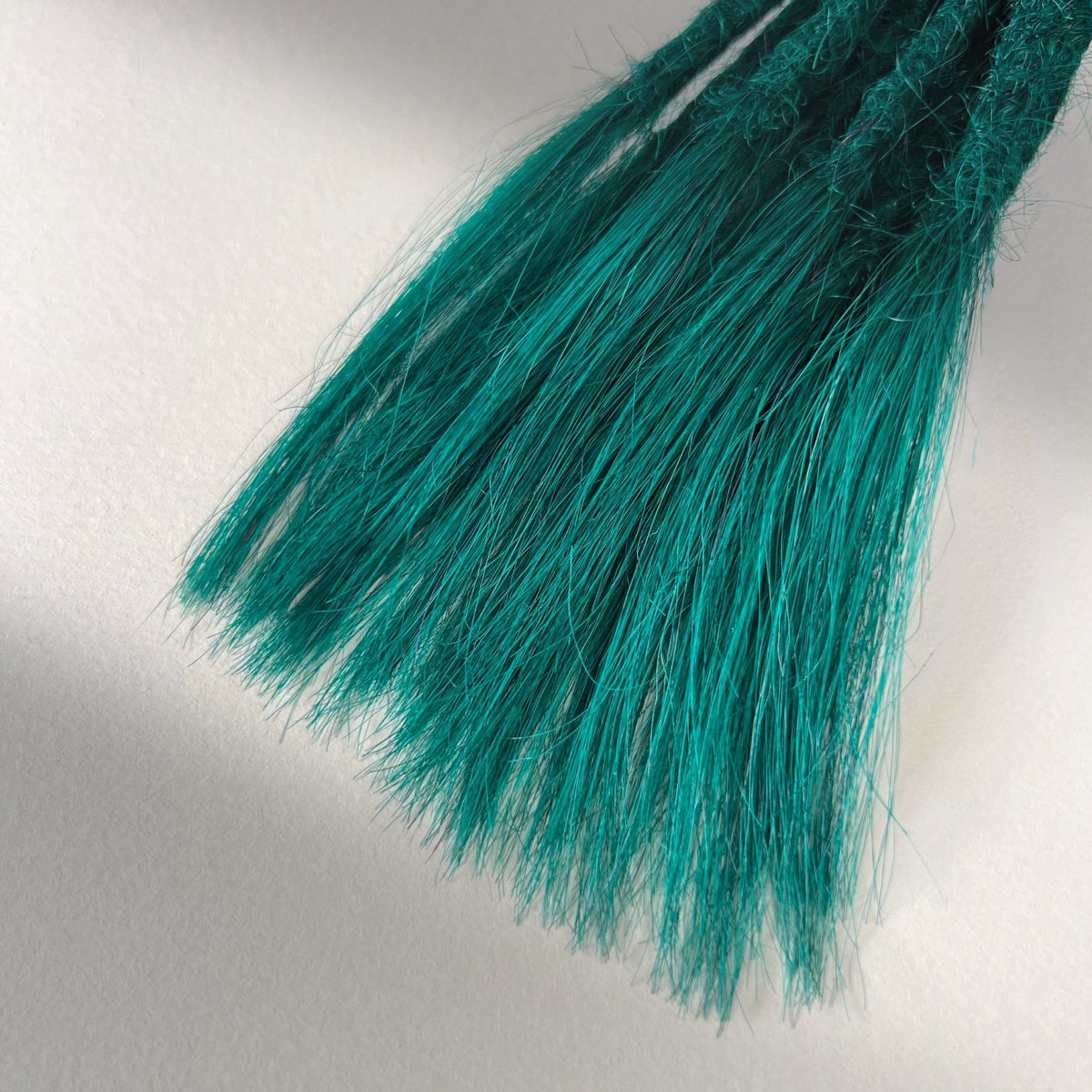 Tip detail of straight loc extensions with open ends in Forest Green.