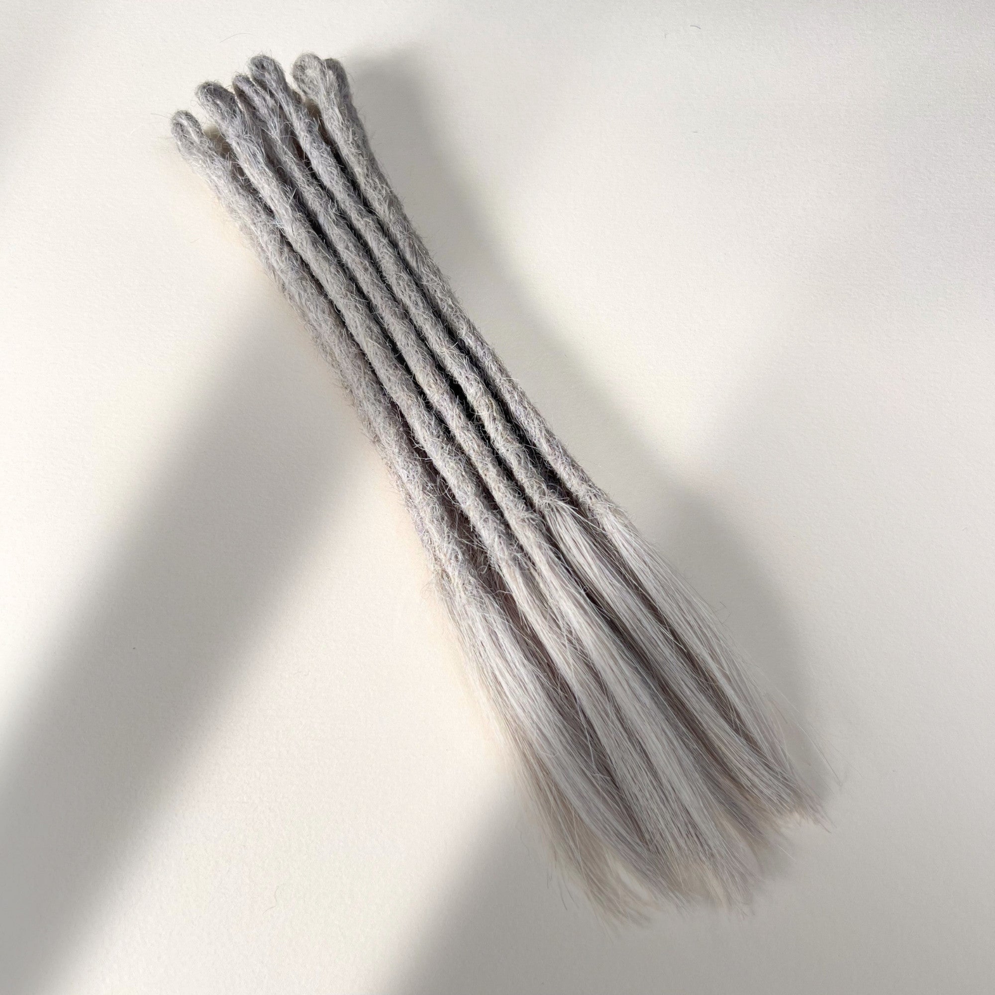 Full view of temporary single-ended straight loc extensions with open ends in Pearl Silver.