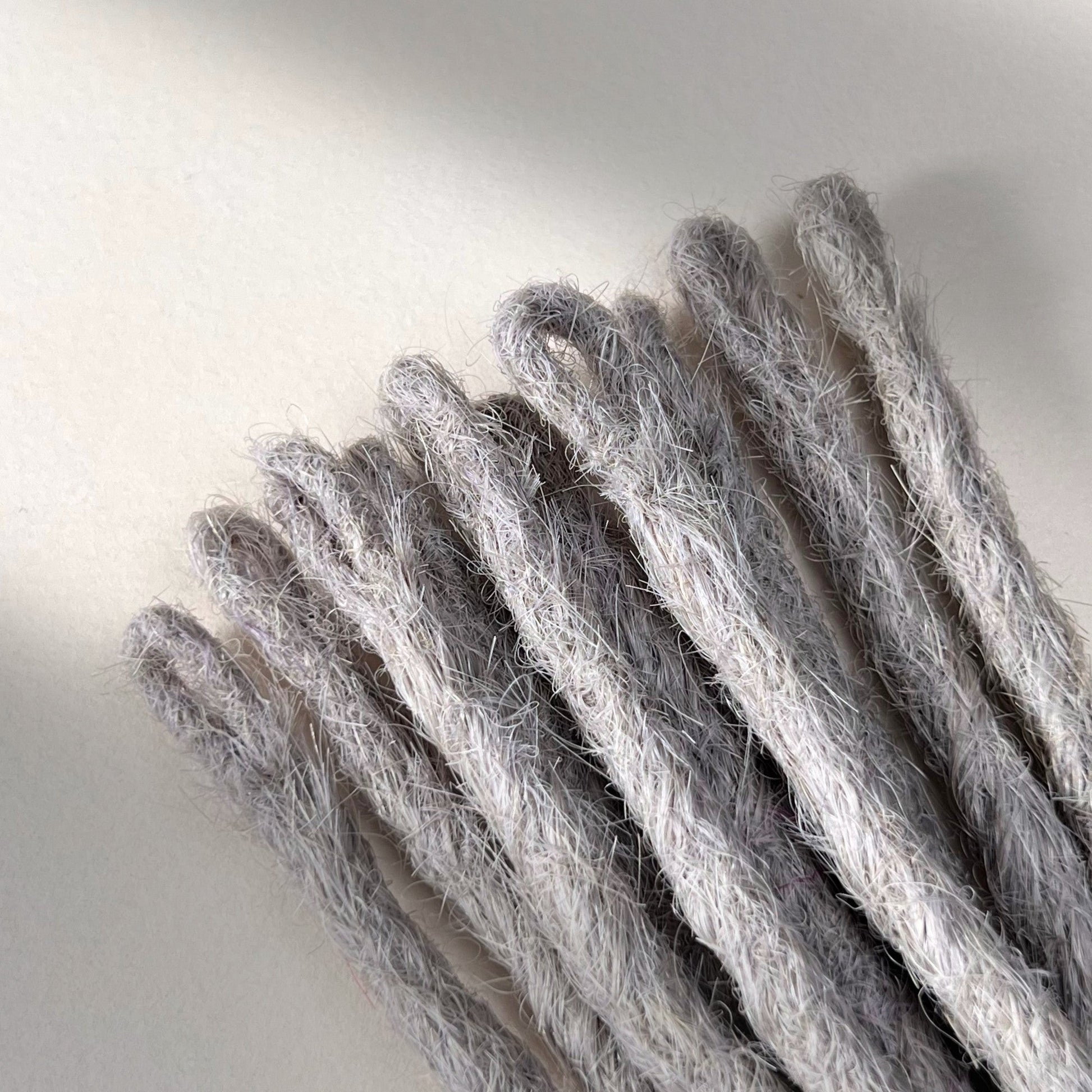 Loop detail of temporary single-ended straight loc extensions with open ends in Pearl Silver.