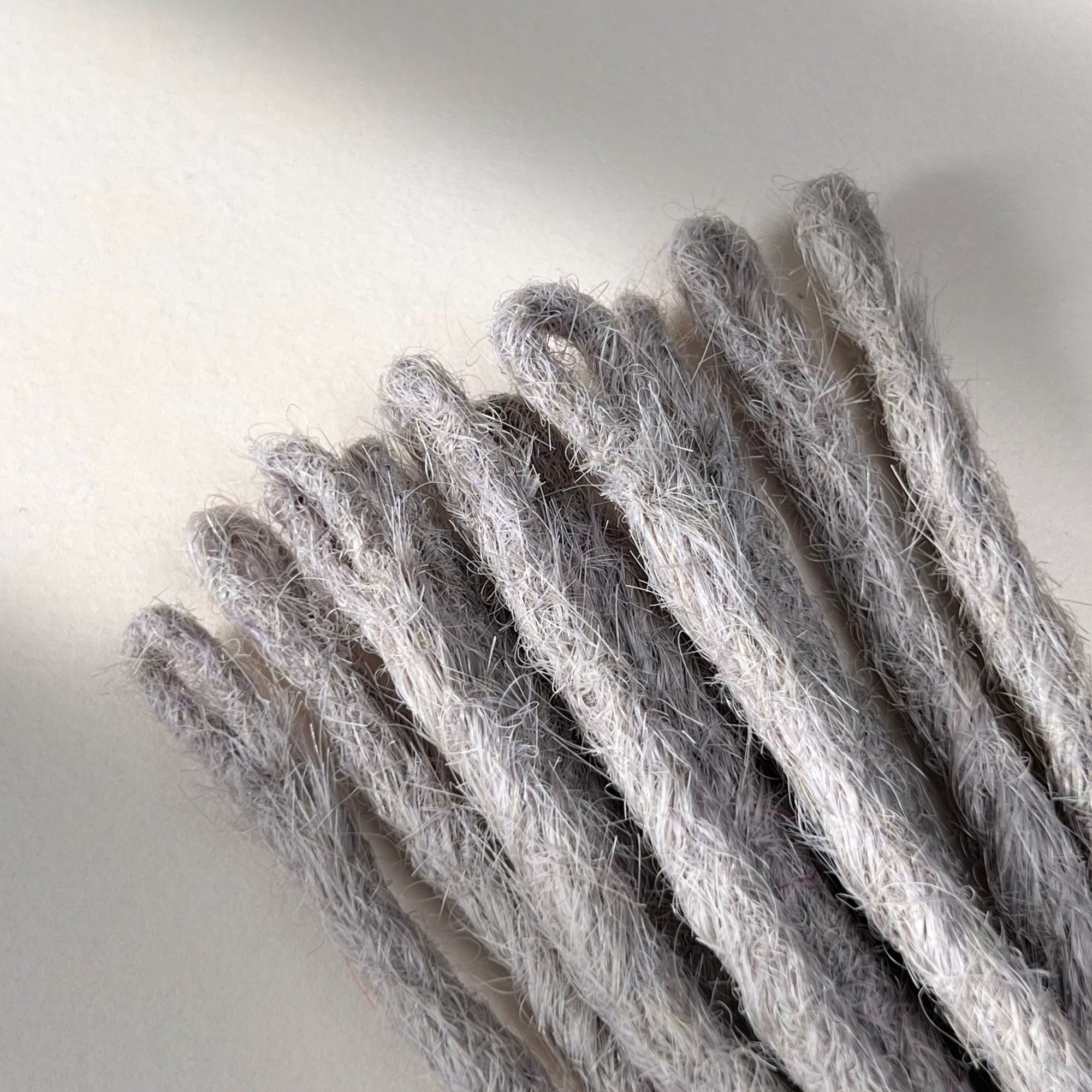 Loop detail of temporary single-ended straight loc extensions with open ends in Pearl Silver.