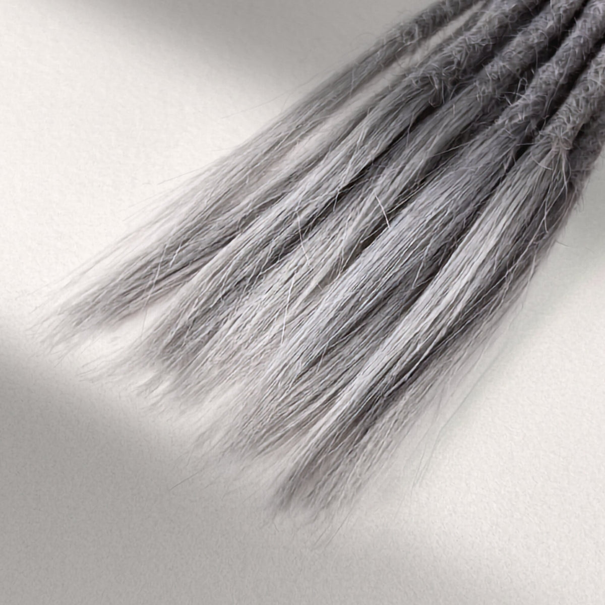 Tip detail of straight loc extensions with open ends in Pearl Silver.