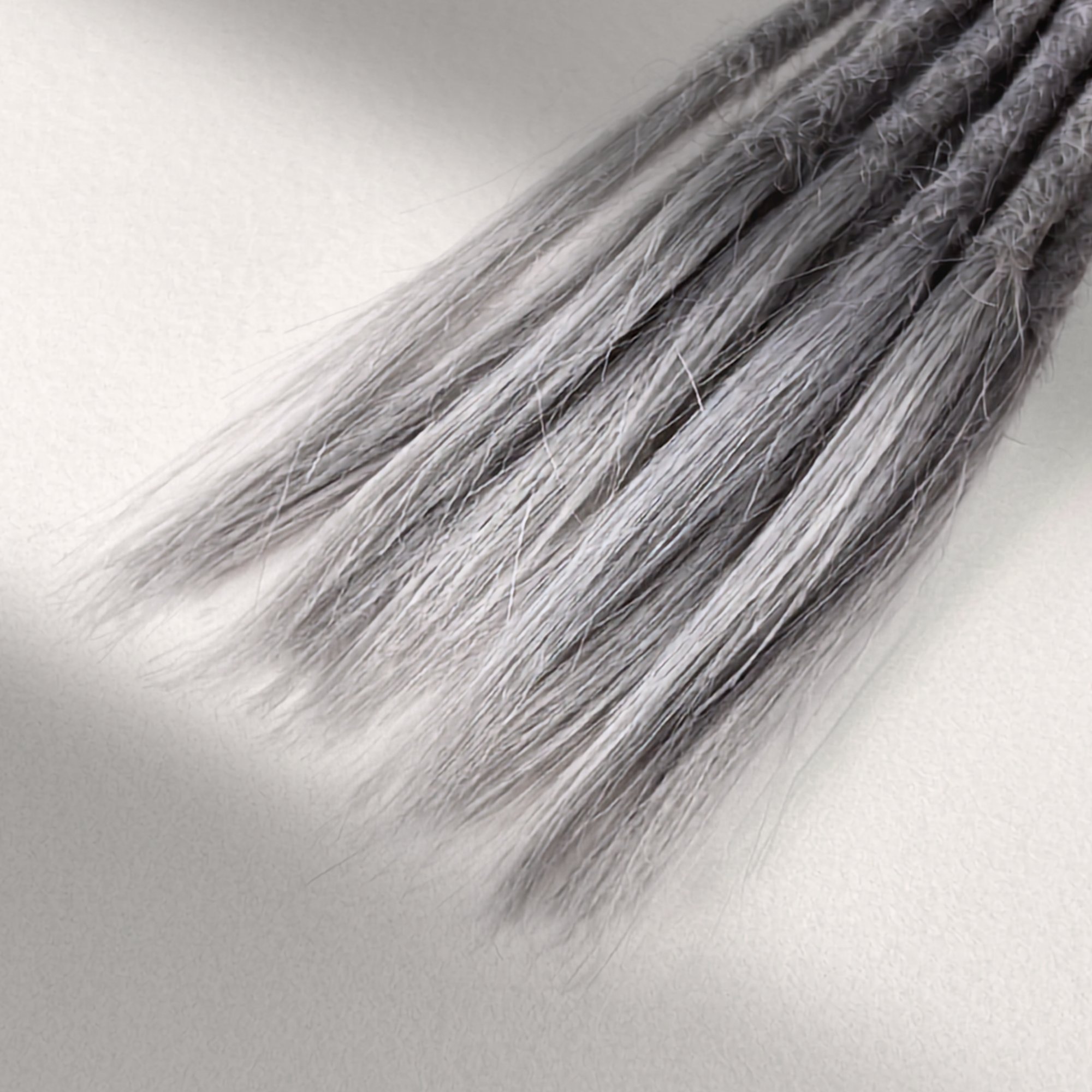 Tip detail of straight loc extensions with open ends in Pearl Silver.