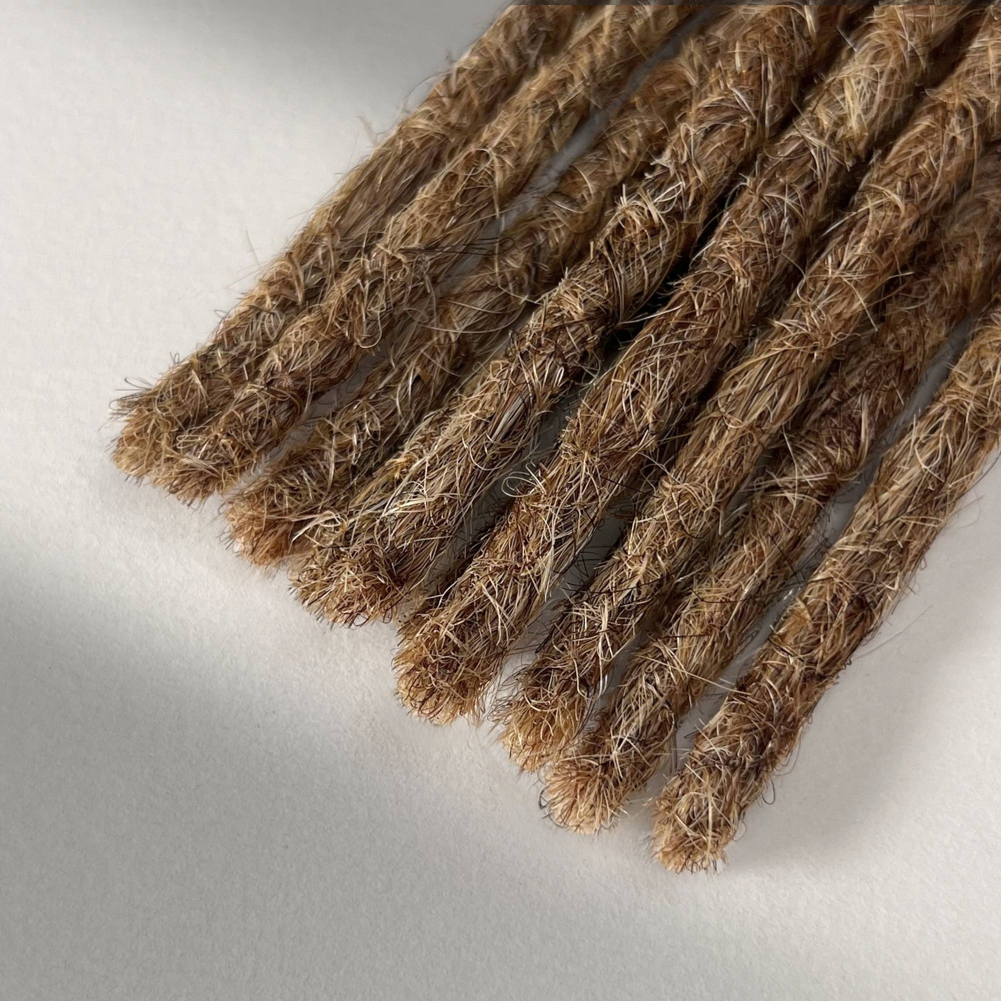 Tip detail of straight loc extensions with blunt ends in Honey Blonde.