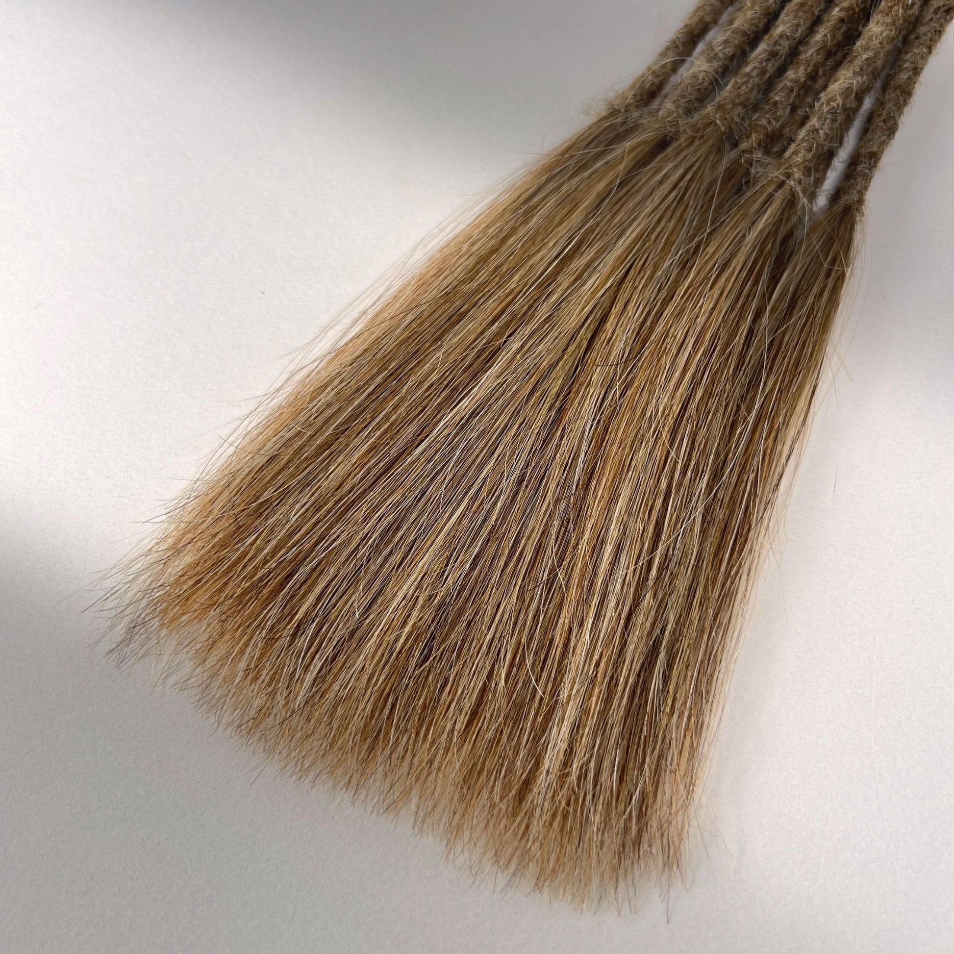 Tip detail of straight loc extensions with long loose ends in Honey Blonde.