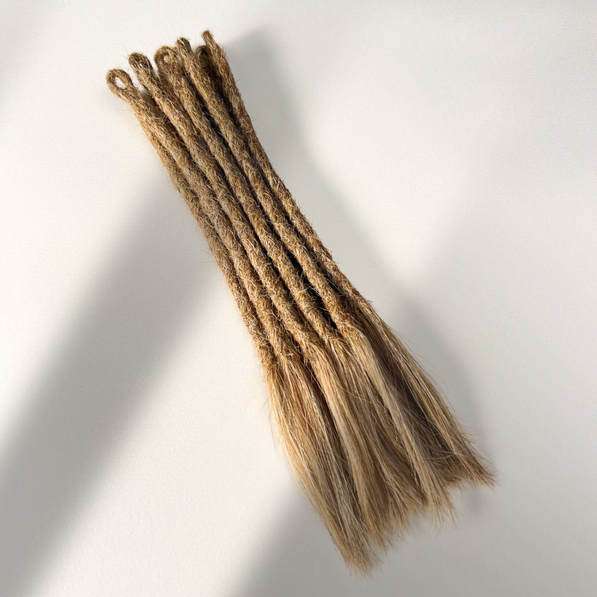Full view of temporary single-ended straight loc extensions with open ends in Honey Blonde.
