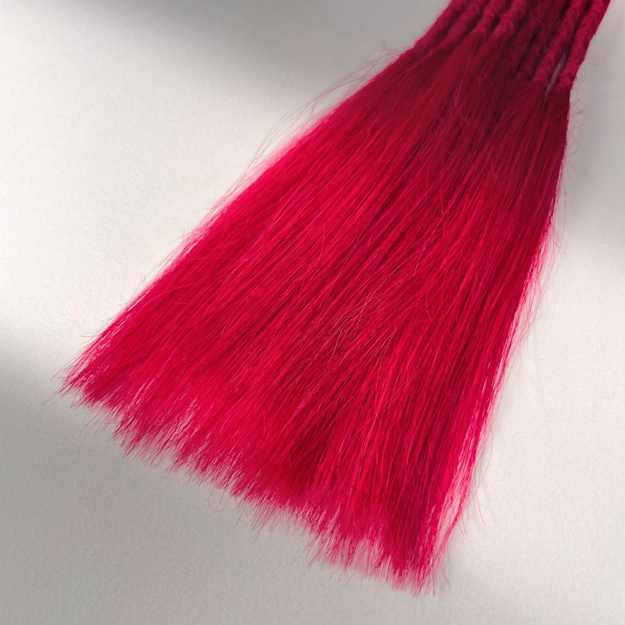 Tip detail of straight loc extensions with long loose ends in Indian Pink.