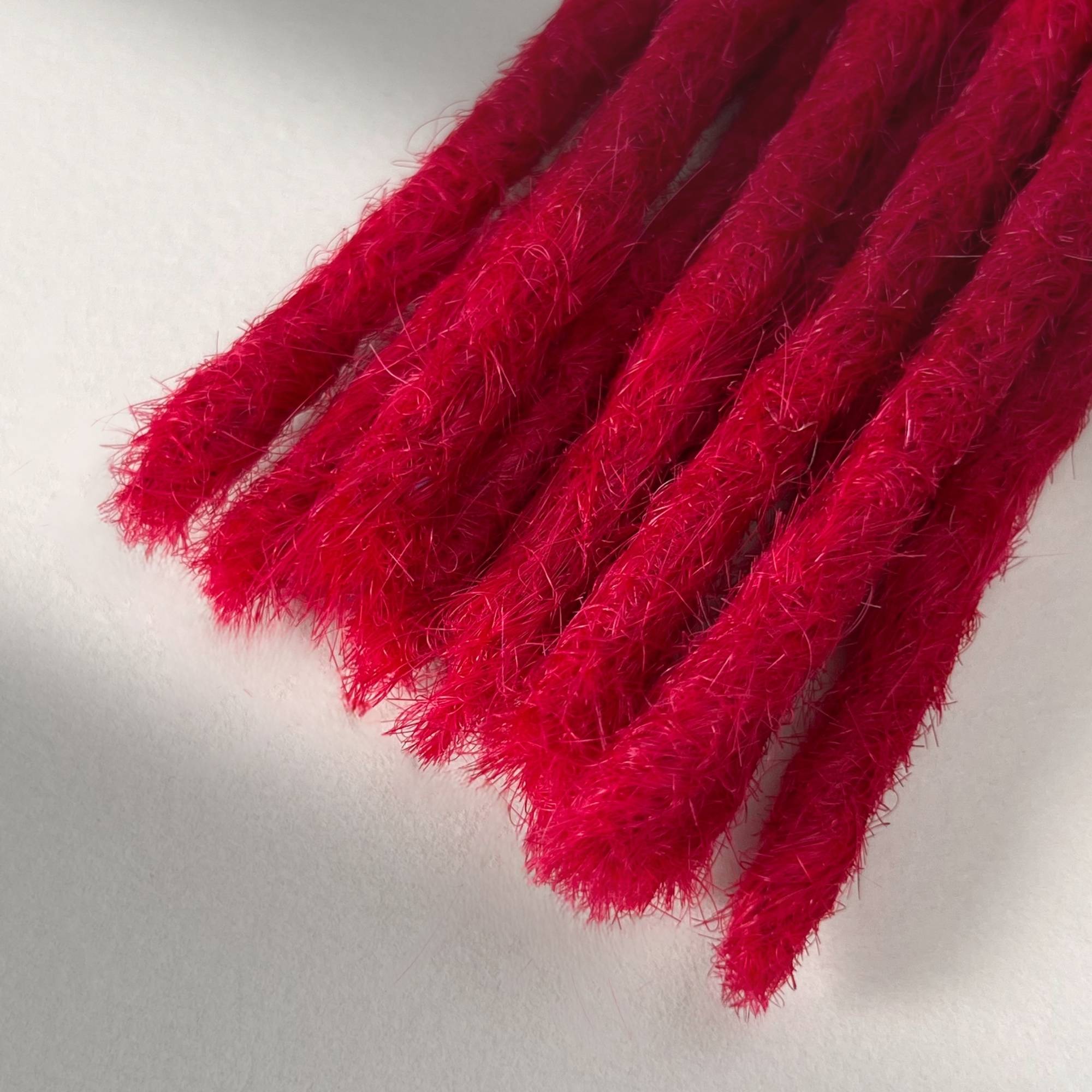 Tip detail of straight loc extensions with blunt ends in Indian Pink.