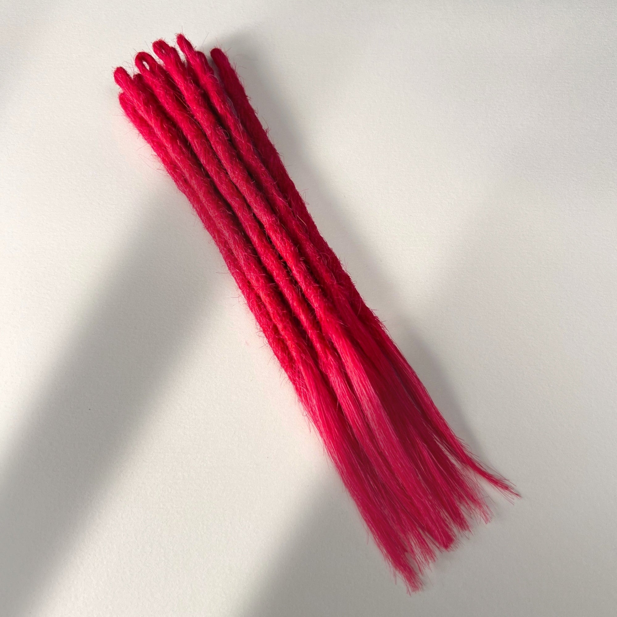 Full view of temporary single-ended straight loc extensions with open ends in Indian Pink.