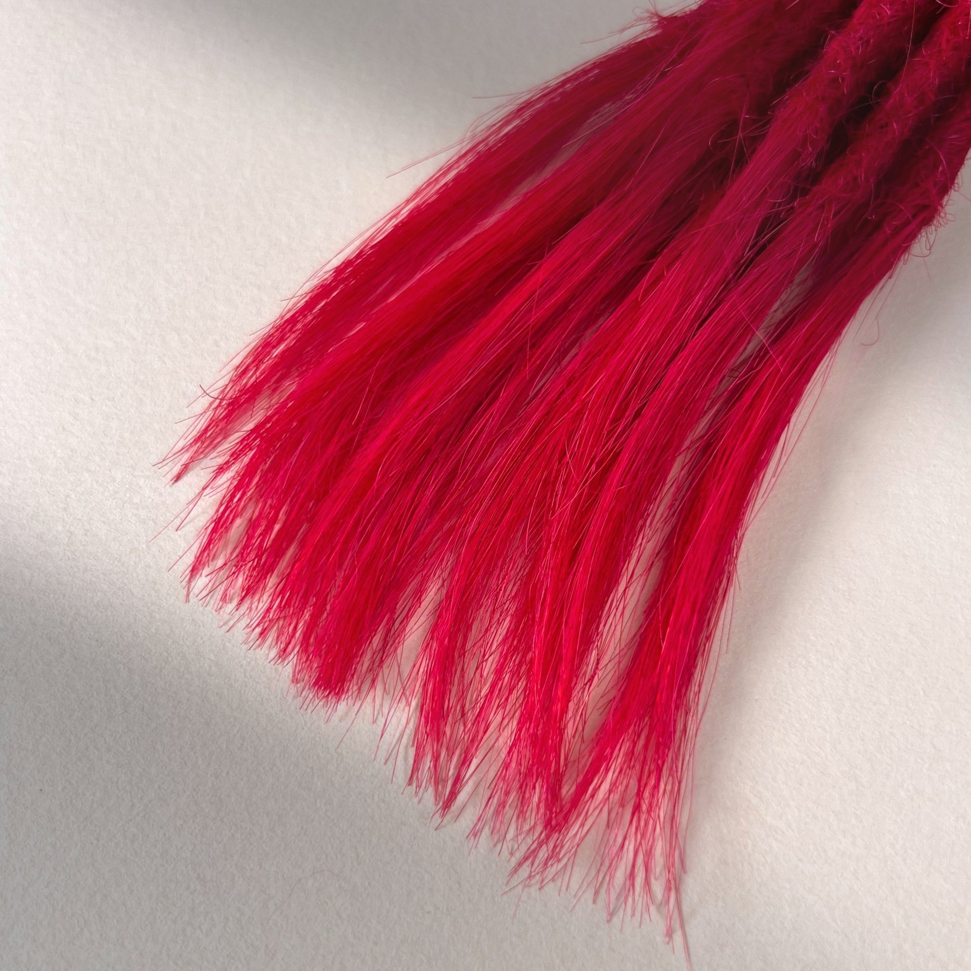 Tip detail of straight loc extensions with open ends in Indian Pink.
