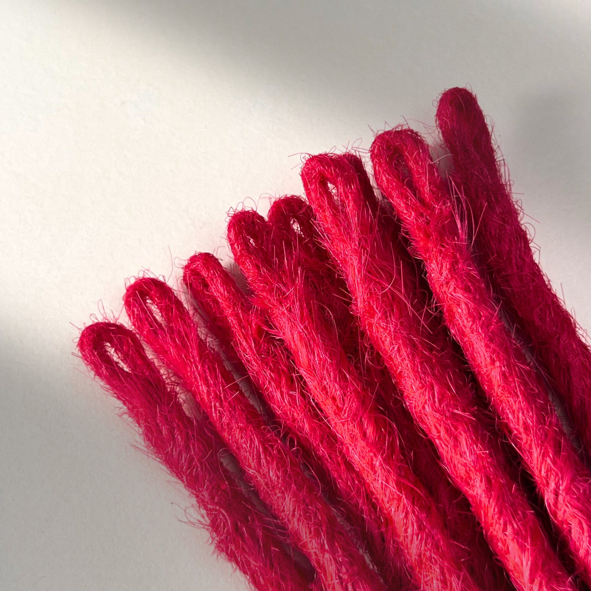 Loop detail of temporary single-ended straight loc extensions in Indian Pink.