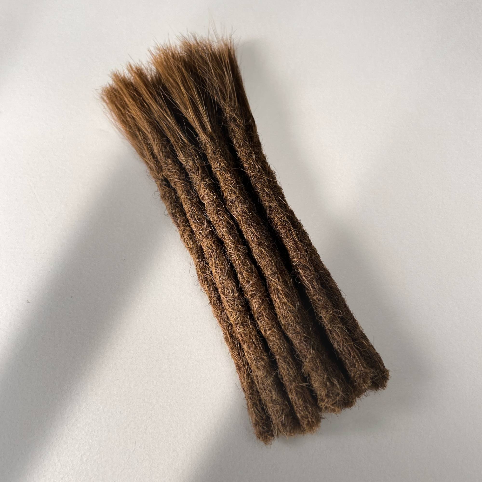 Full view of permanent straight loc extensions with blunt ends in Honey Brown.