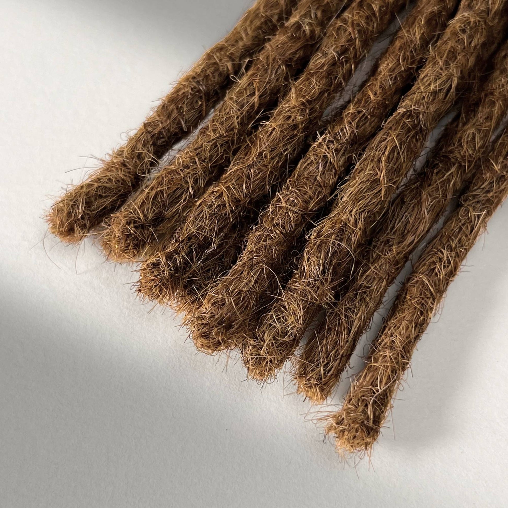 Tip detail of straight loc extensions with blunt ends in Honey Brown.