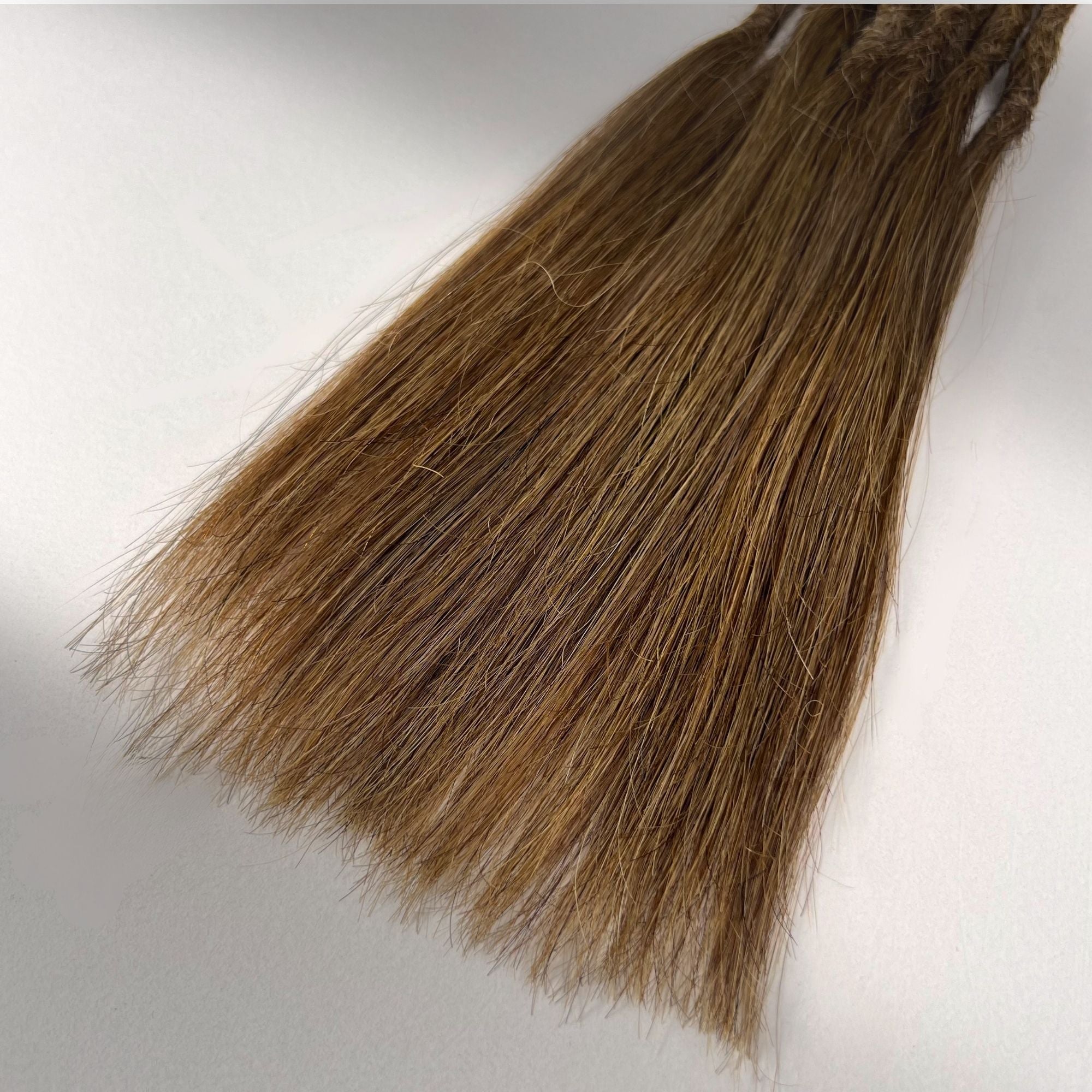 Tip detail of straight loc extensions with long loose ends in Honey Brown.