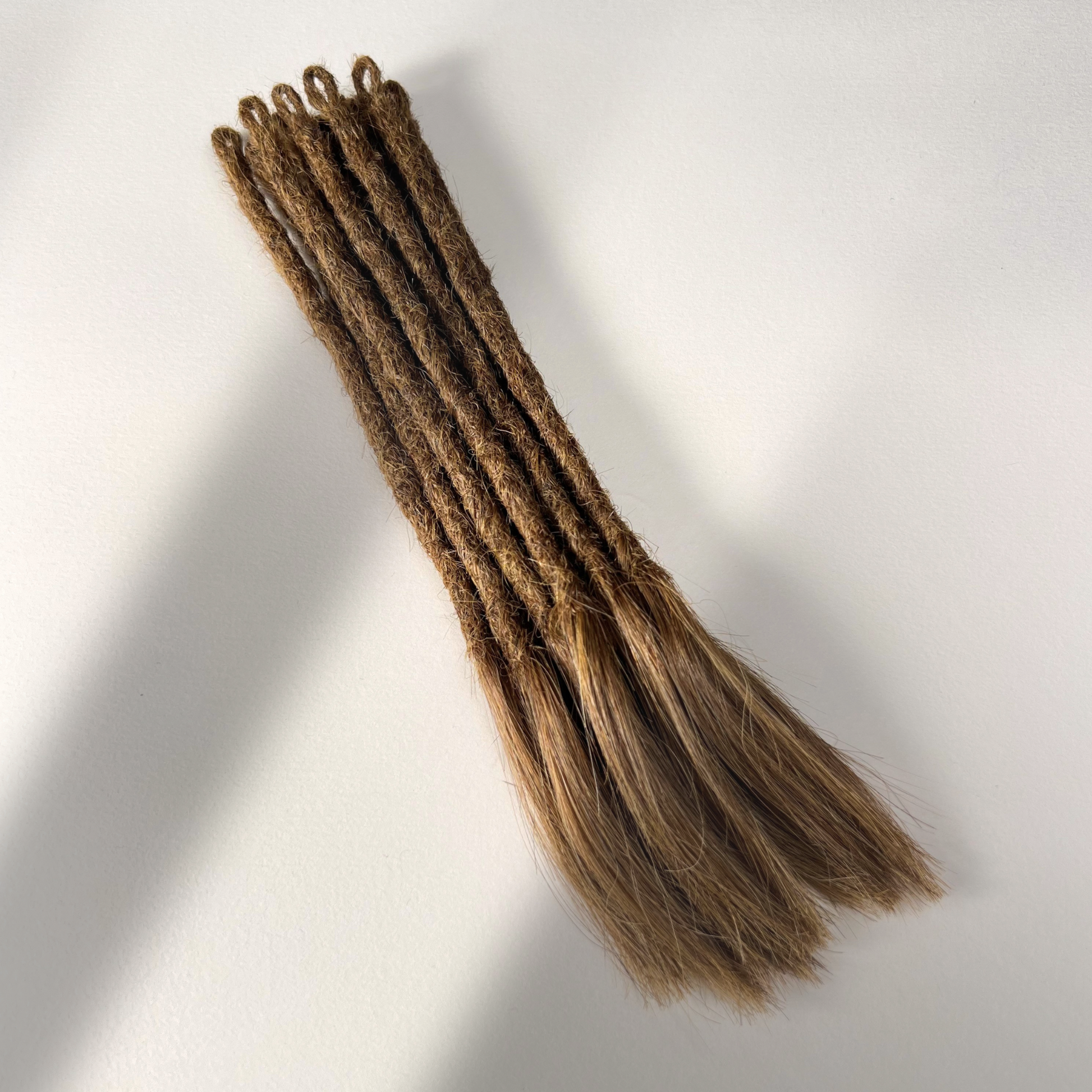 Full view of temporary single-ended straight loc extensions with open ends in Honey Brown.