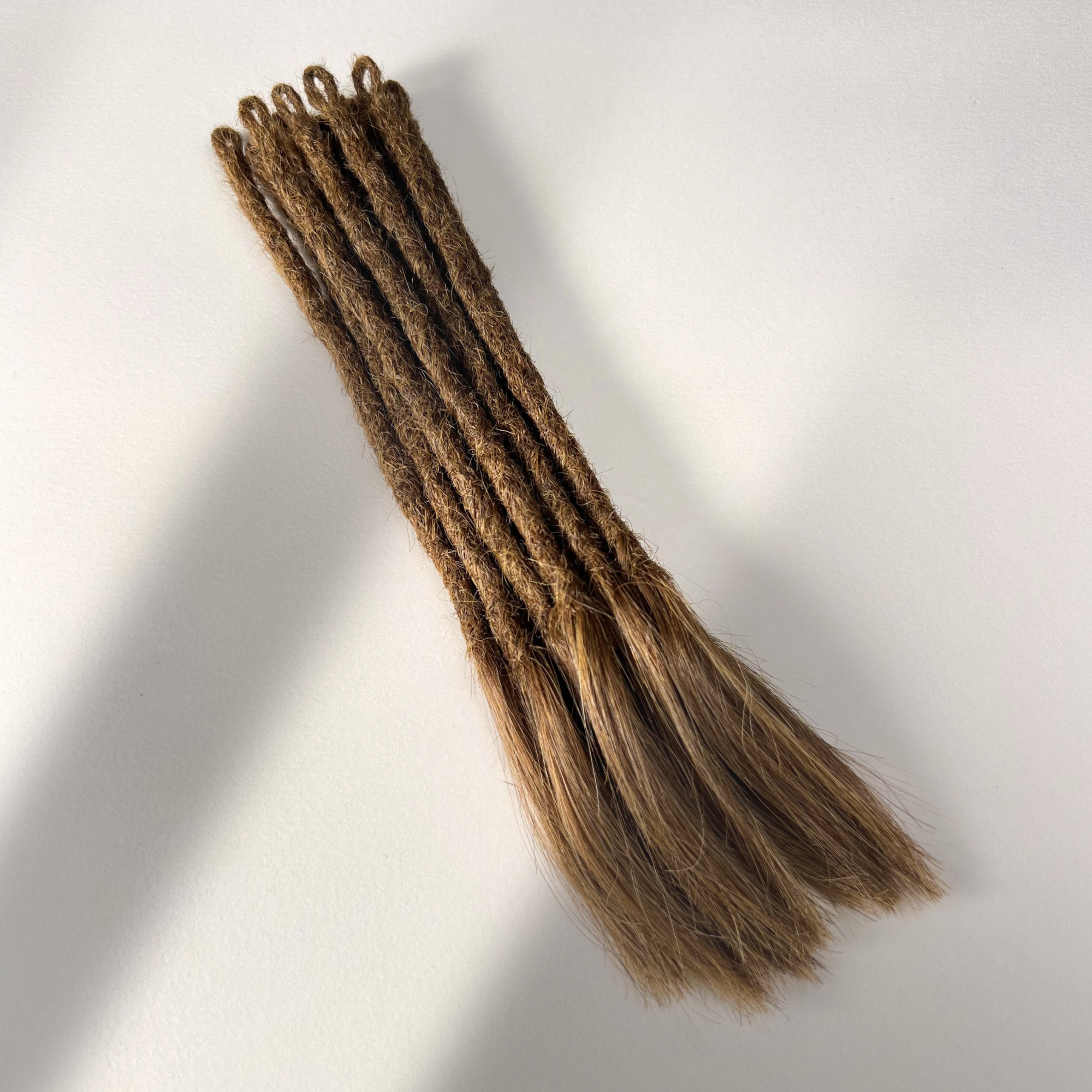 Full view of temporary single-ended straight loc extensions with open ends in Honey Brown.