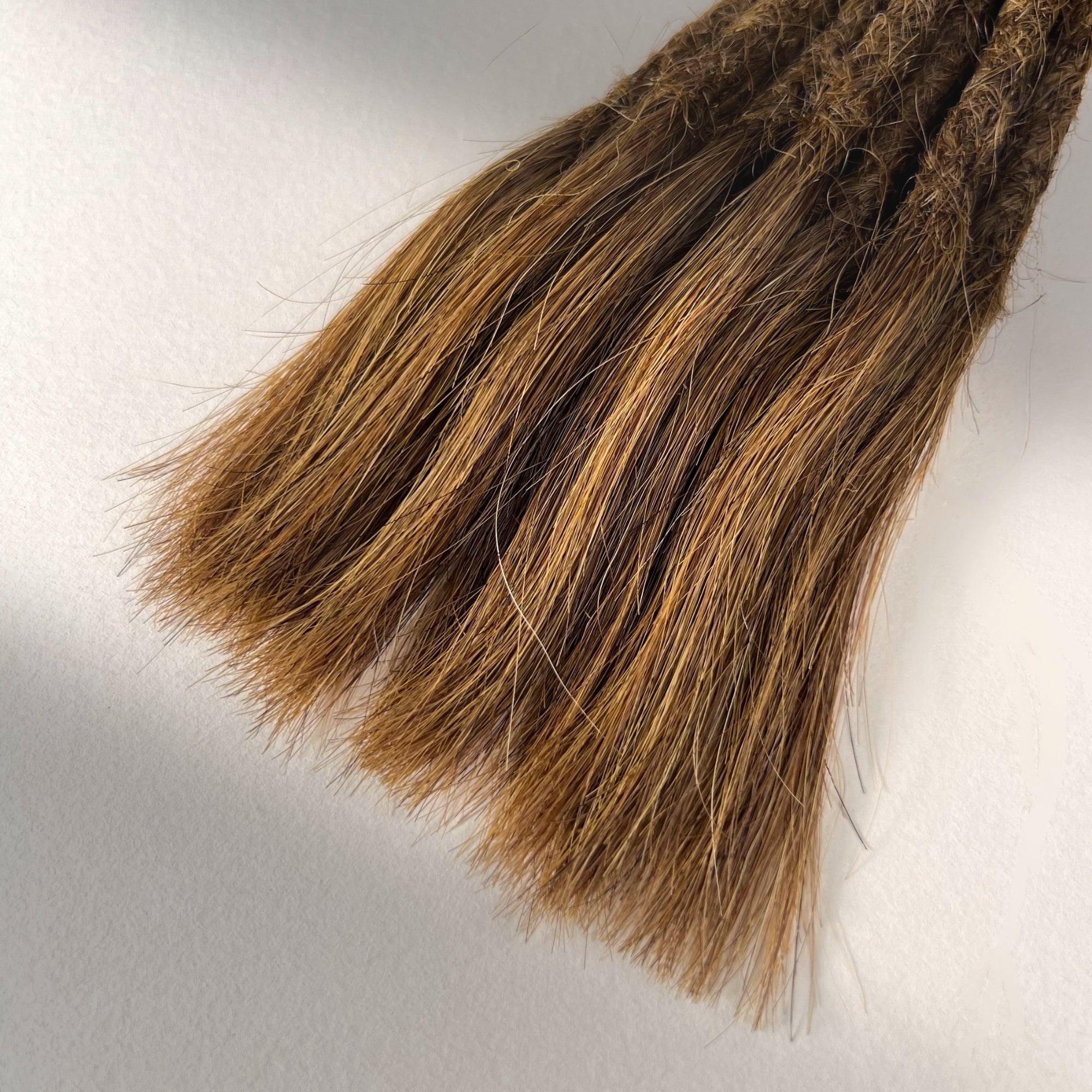 Tip detail of straight loc extensions with open ends in Honey Brown.