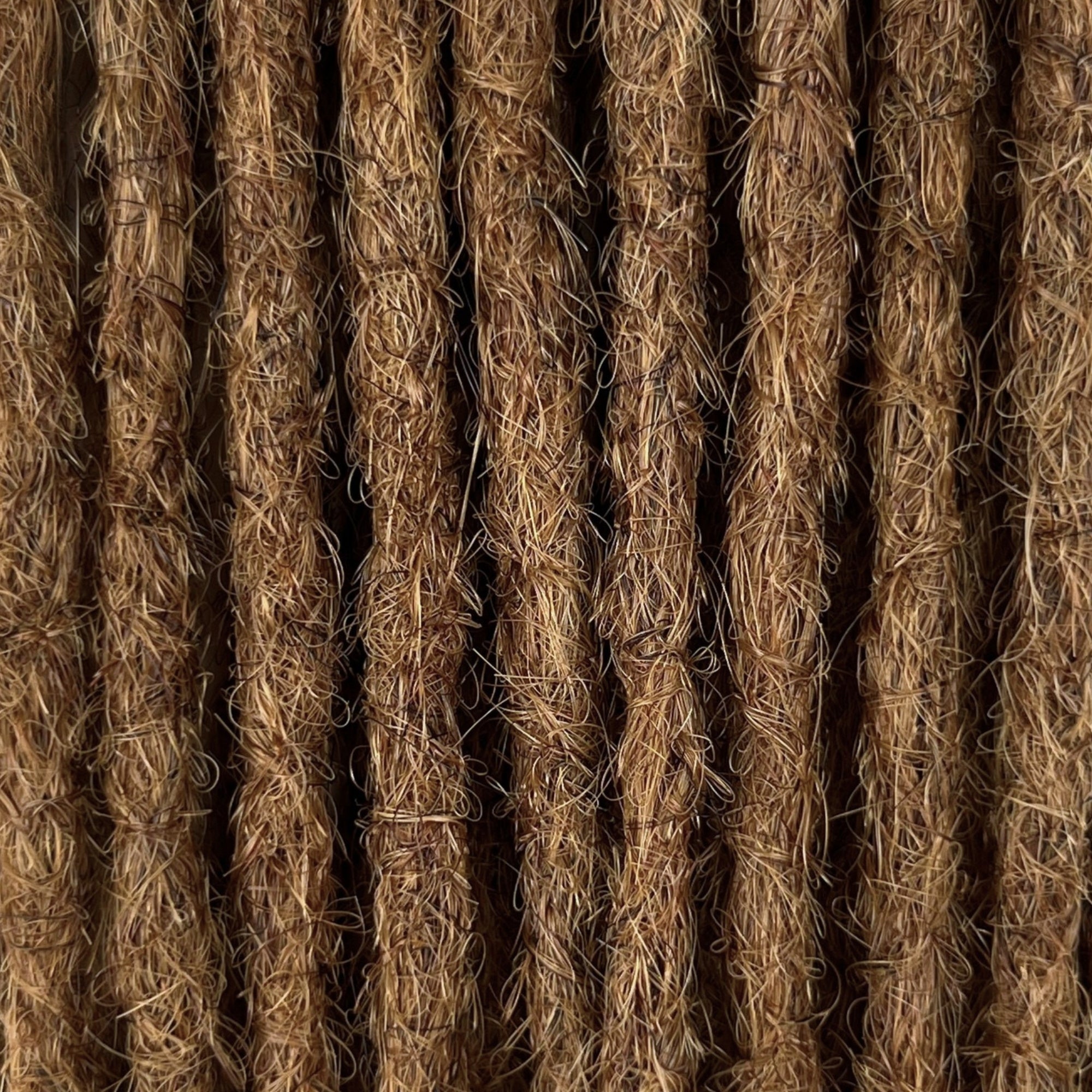 Close-up of straight loc extensions in Honey Brown, showing the texture and color.