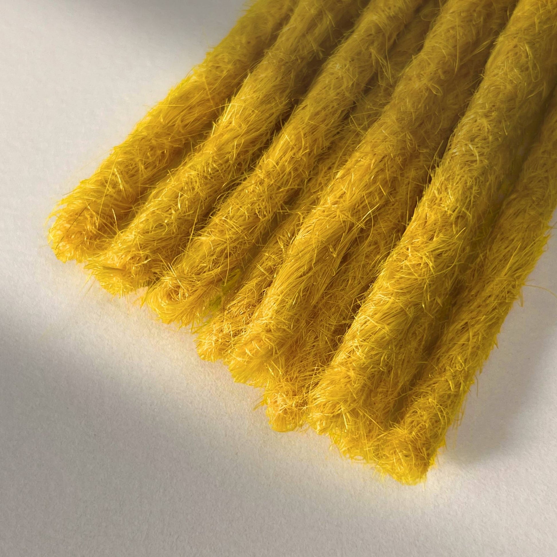 Tip detail of straight loc extensions with blunt ends in Lemon Yellow.