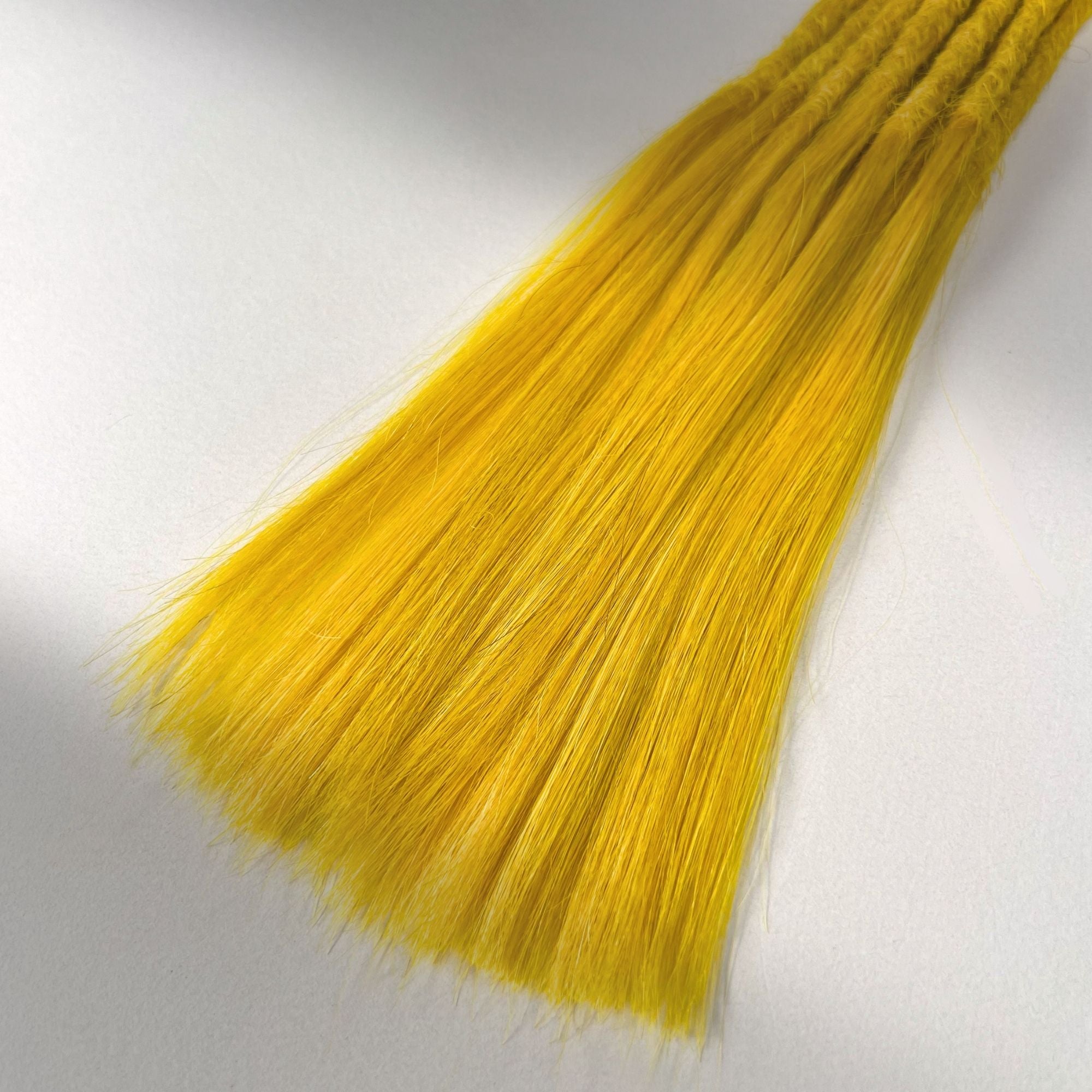 Tip detail of straight loc extensions with long loose ends in Lemon Yellow.