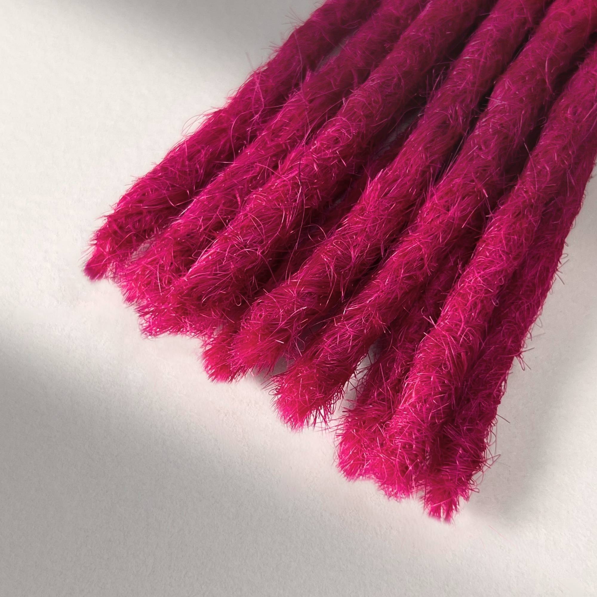 Tip detail of straight loc extensions with blunt ends in Magenta Pink.