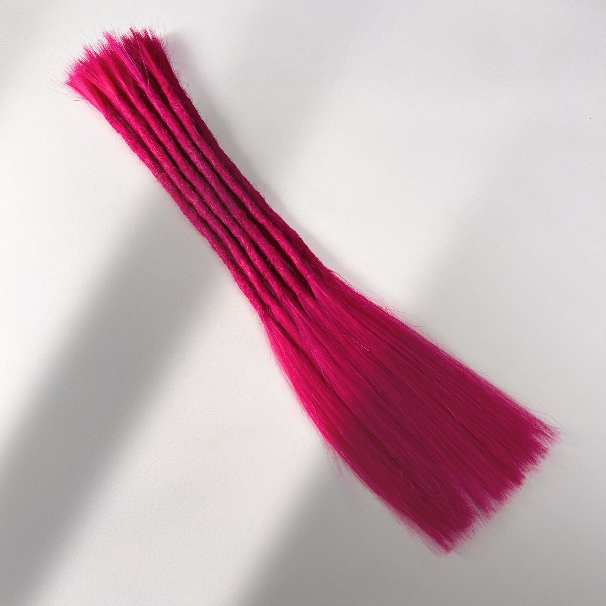 Full view of permanent straight loc extensions with long loose ends in Magenta Pink.