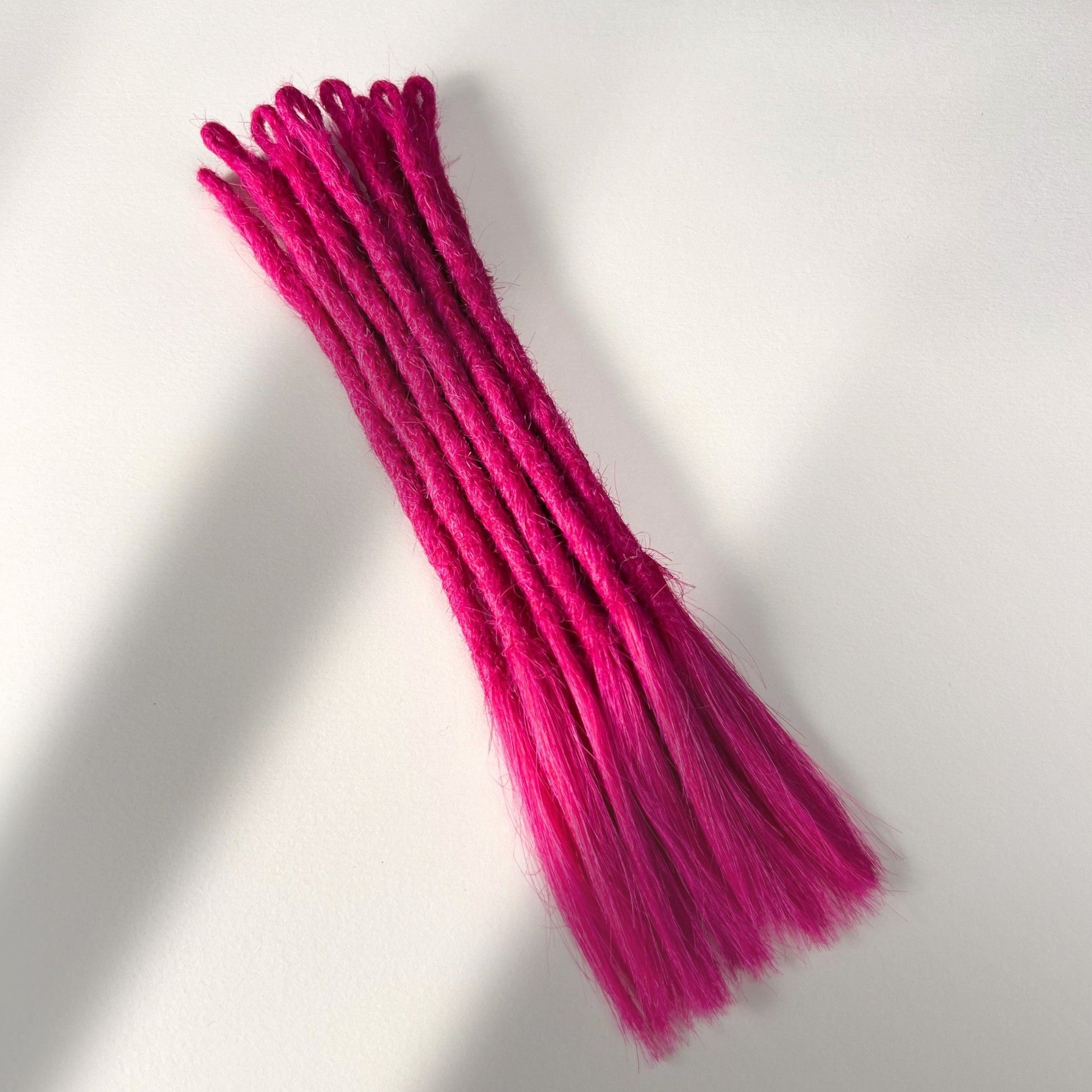Full view of temporary single-ended straight loc extensions with open ends in Magenta Pink.