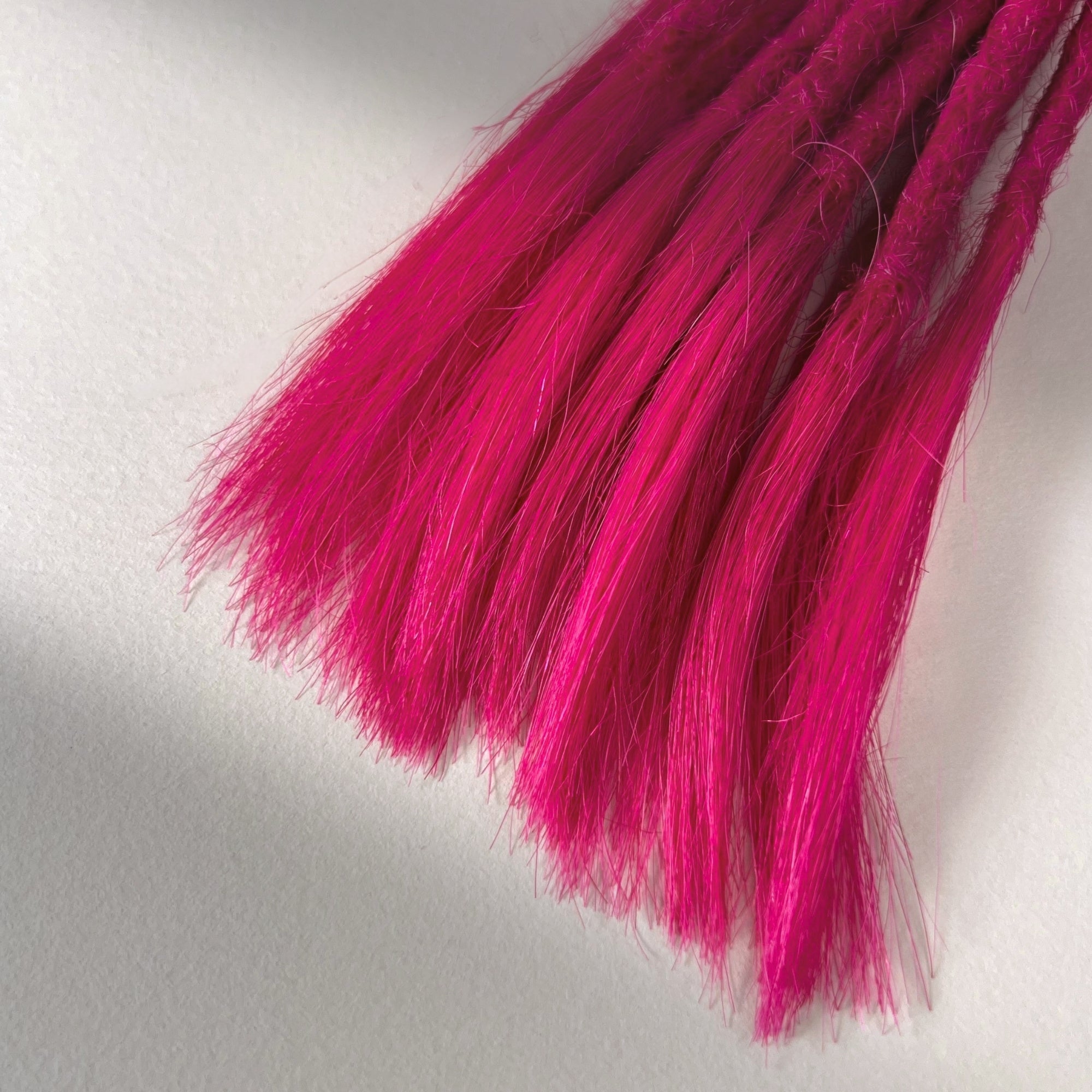 Tip detail of straight loc extensions with open ends in Magenta Pink.