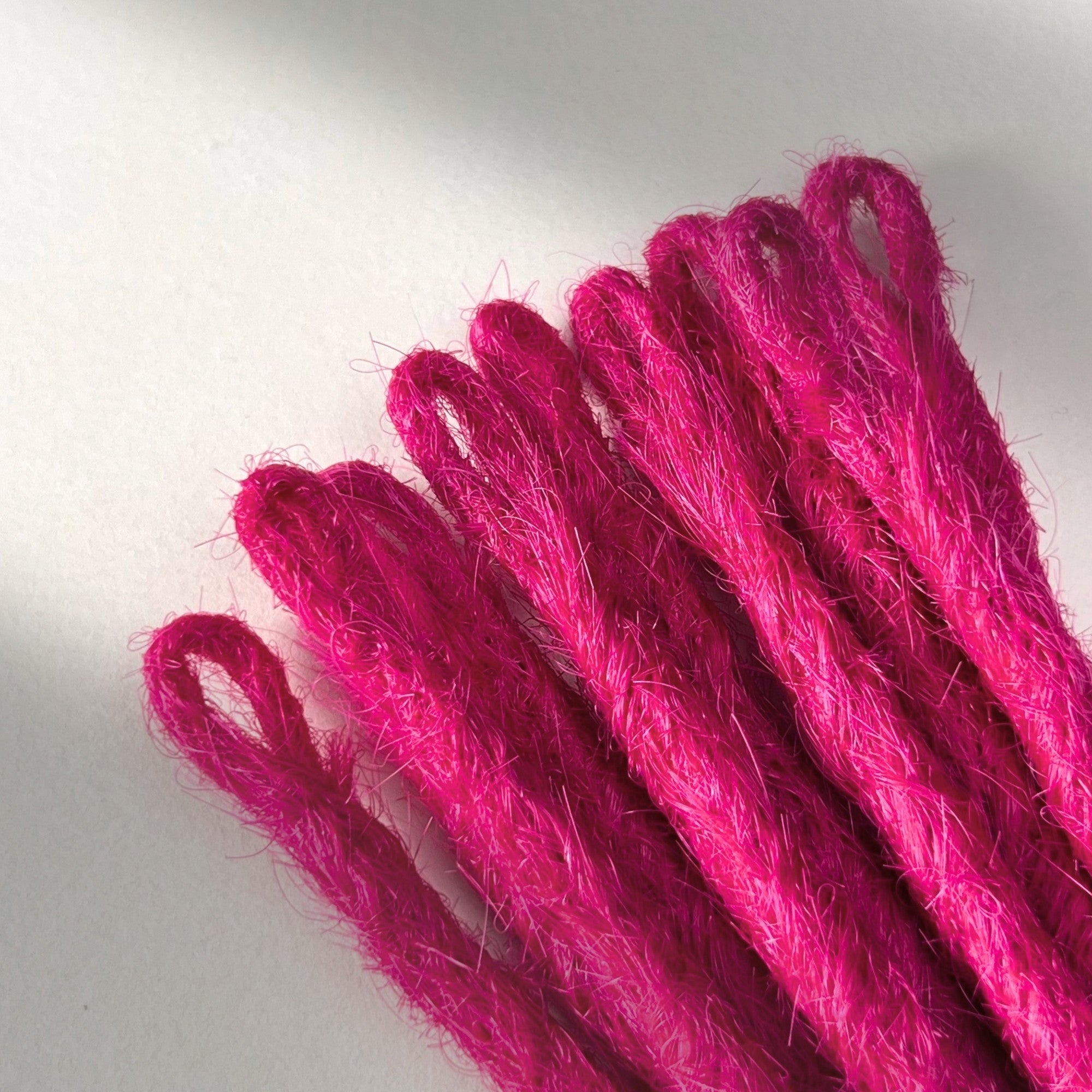 Loop detail of temporary single-ended straight loc extensions in Magenta Pink.