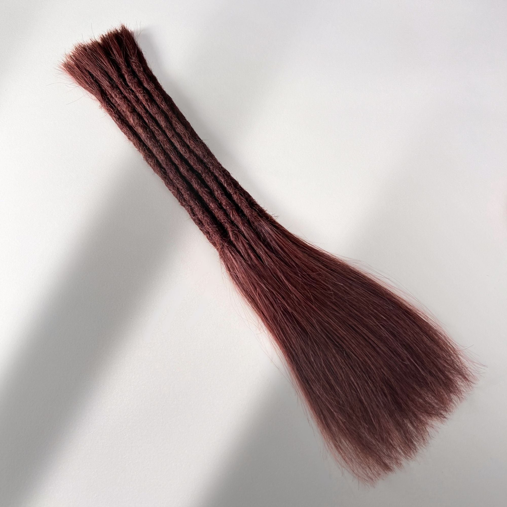 Full view of permanent straight loc extensions with long loose ends in Warm Mahogany Red.