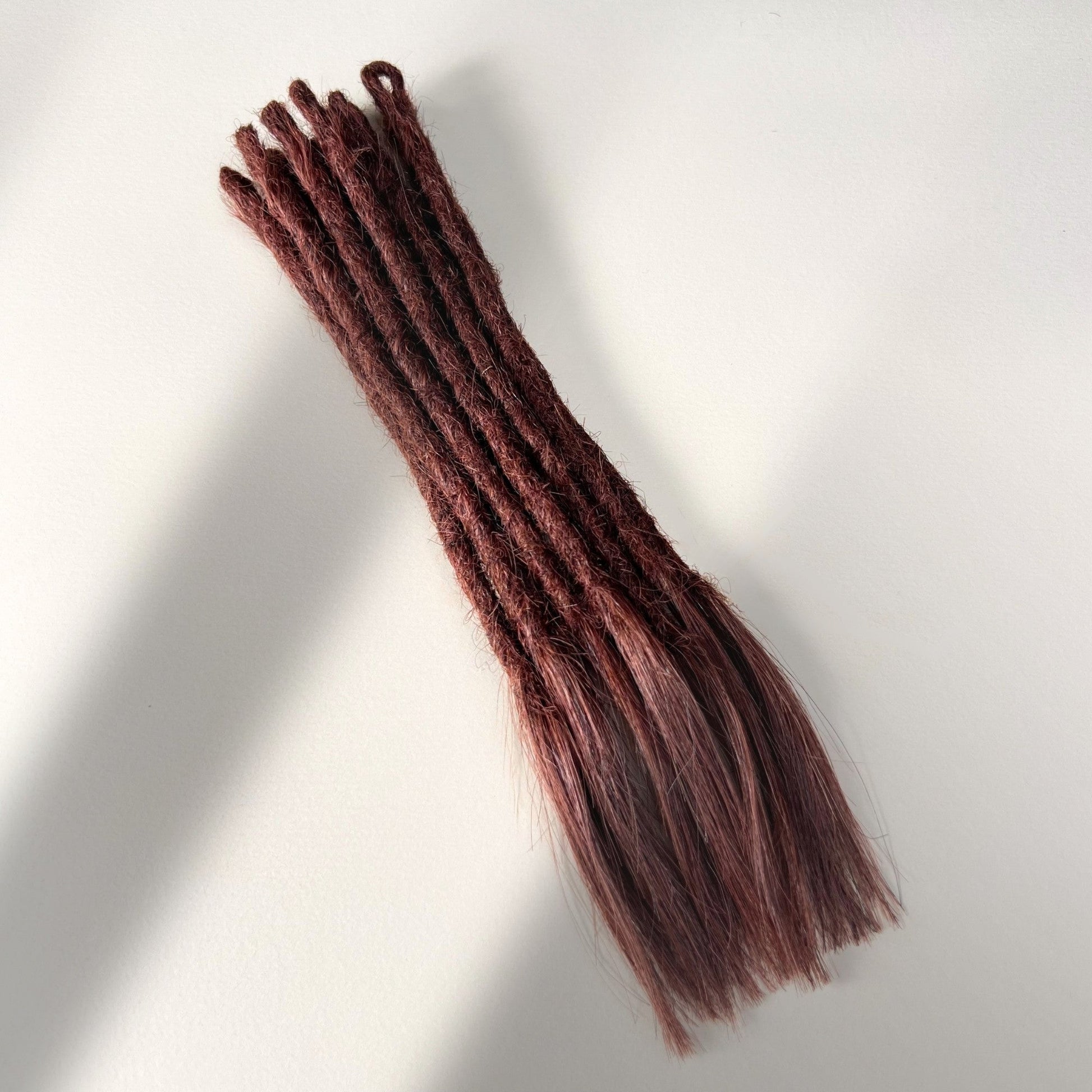 Full view of temporary single-ended straight loc extensions with open ends in Warm Mahogany Red.