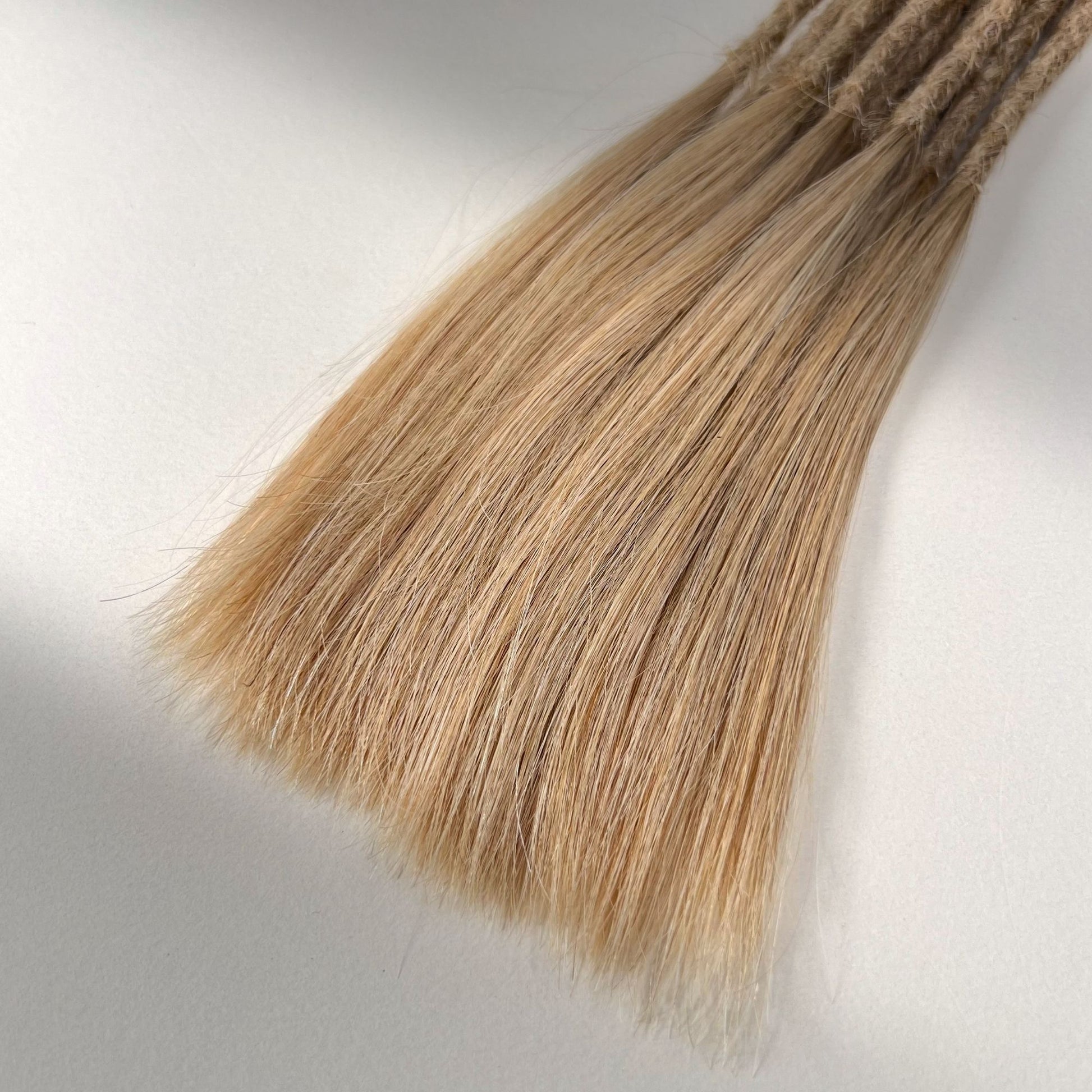 Tip detail of straight loc extensions with long loose ends in Vanilla Blonde.
