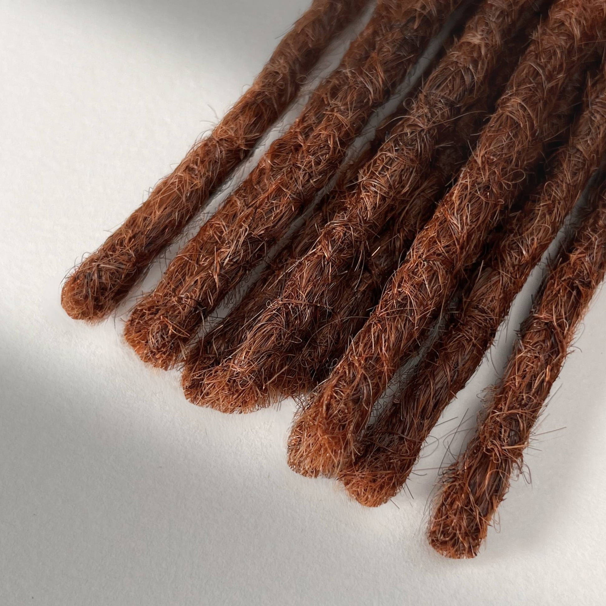 Tip detail of straight loc extensions with blunt ends in Warm Maple Copper.
