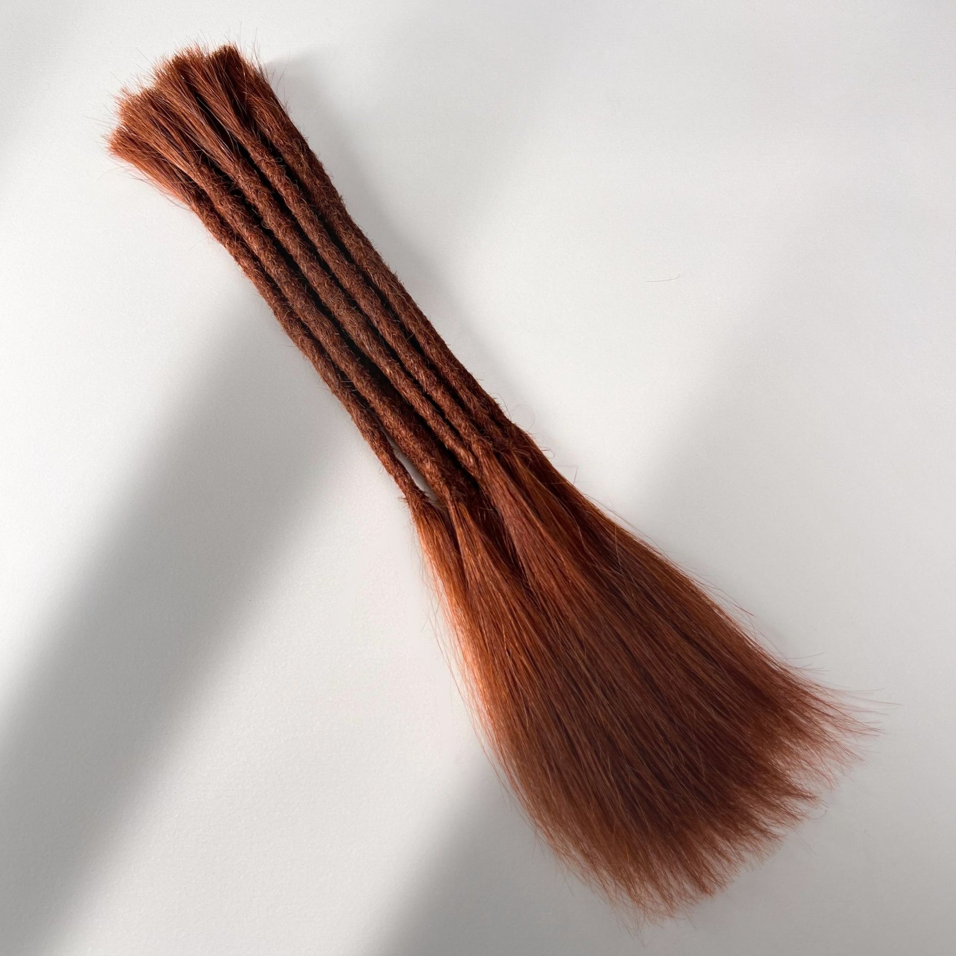 Full view of permanent straight loc extensions with long loose ends in Warm Maple Copper.