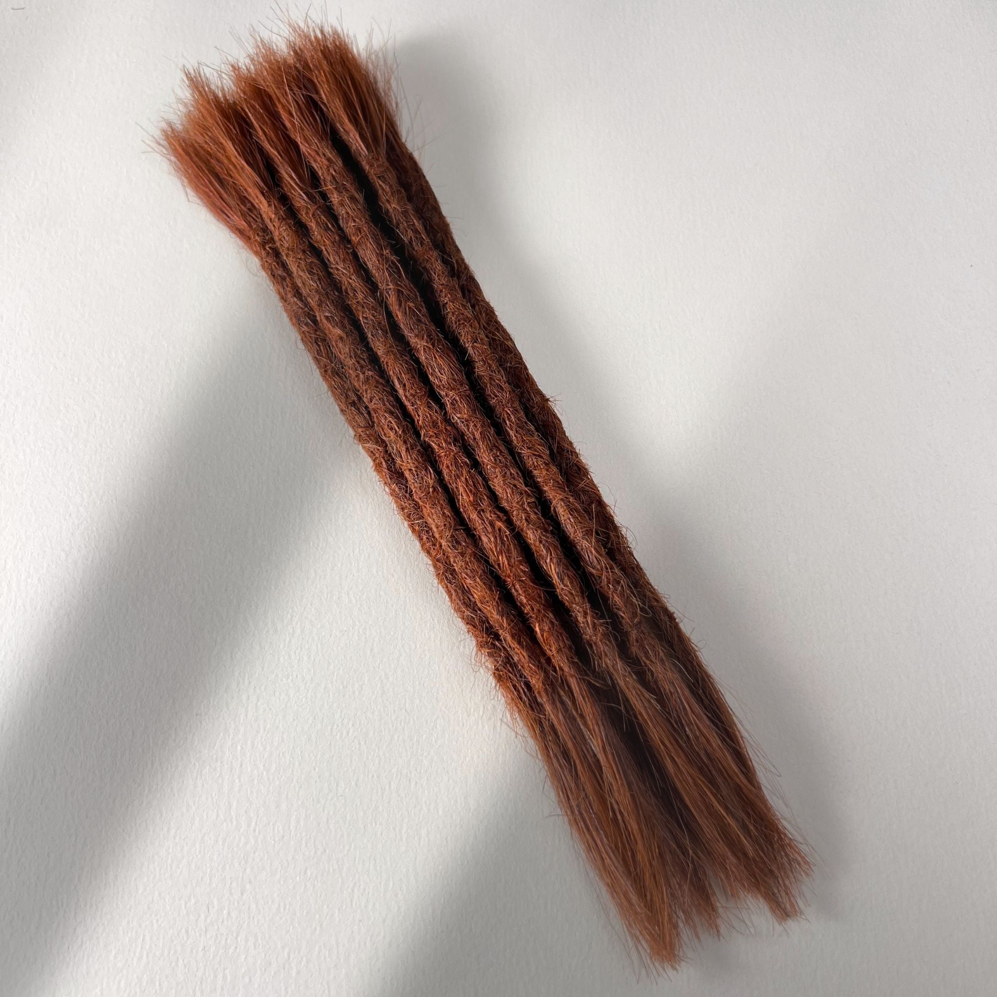 Full view of permanent straight loc extensions with open ends in Warm Maple Copper.