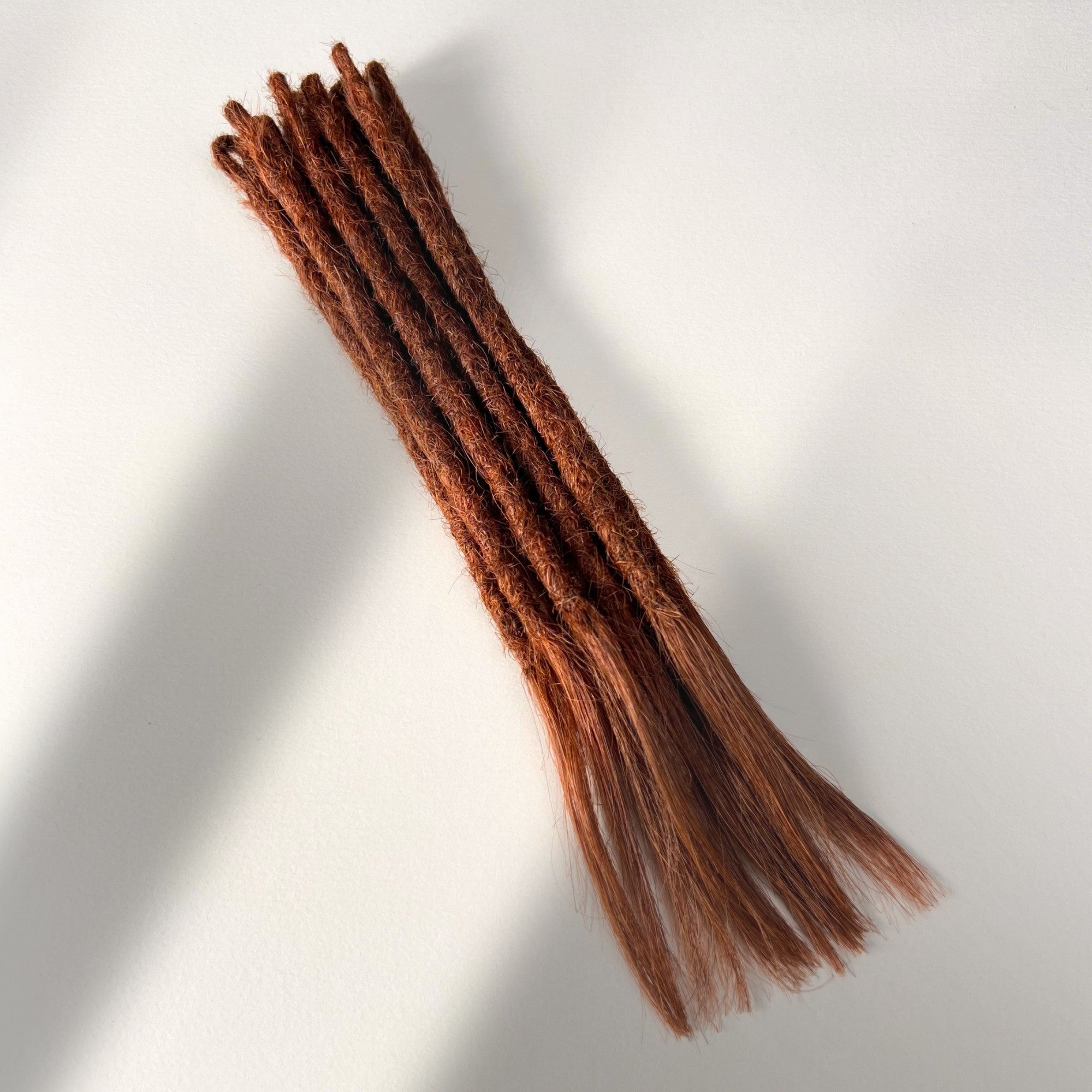 Full view of temporary single-ended straight loc extensions with open ends in Warm Maple Copper.