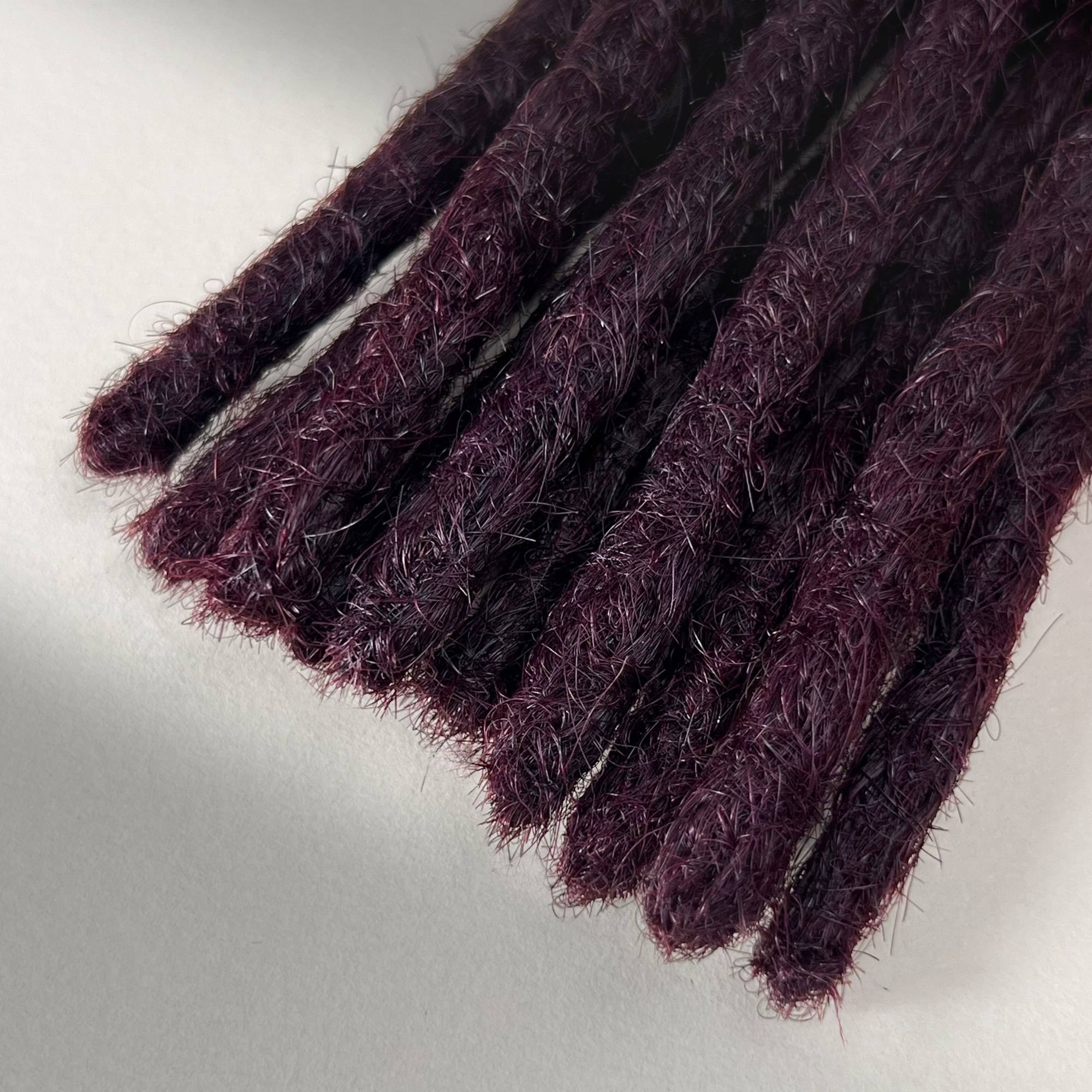 Tip detail of straight loc extensions with blunt ends in Warm Marsala Red.