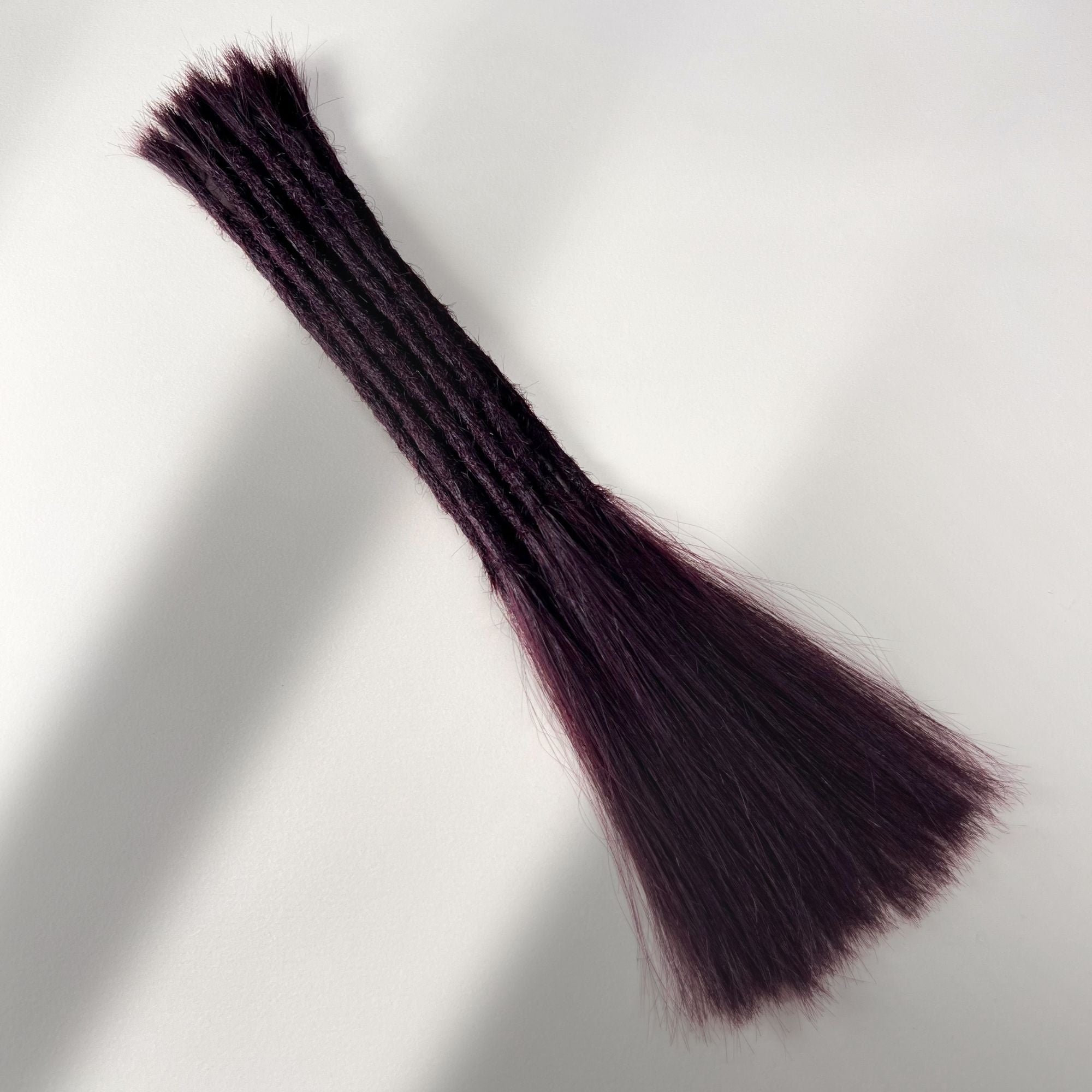 Full view of permanent straight loc extensions with long loose ends in Warm Marsala Red.