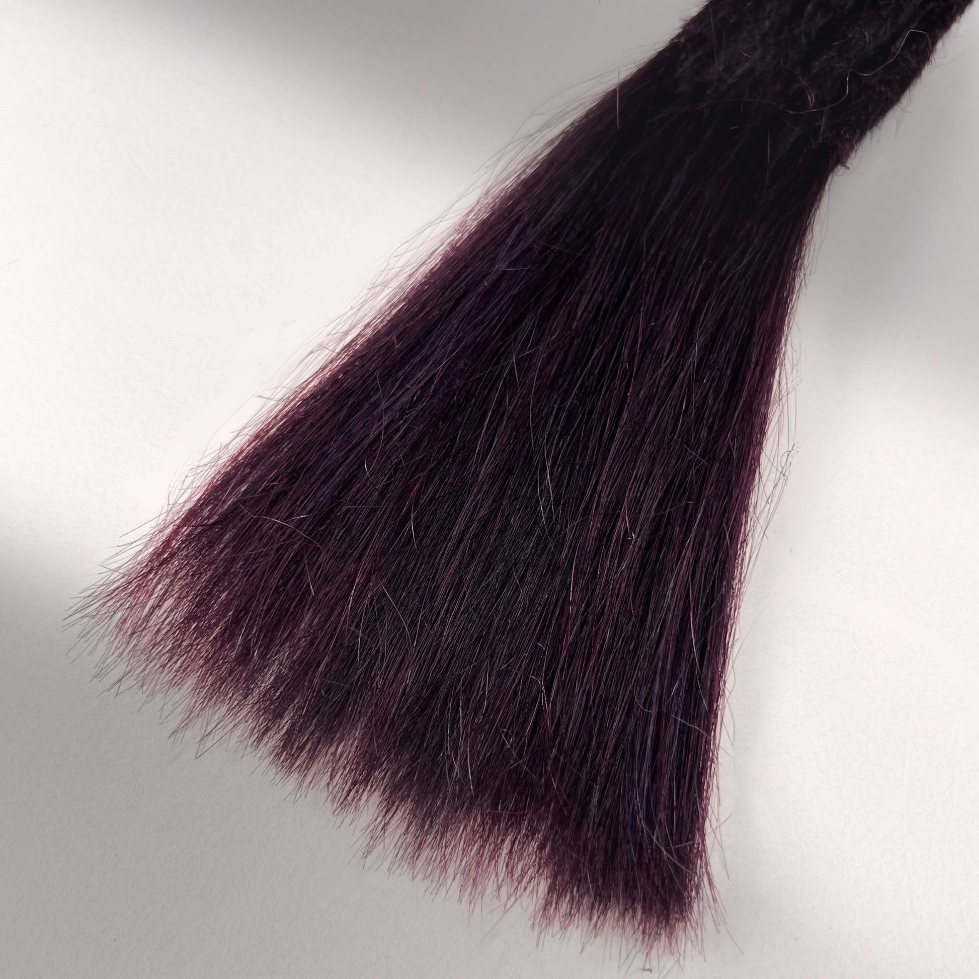 Tip detail of straight loc extensions with long loose ends in Warm Marsala Red.