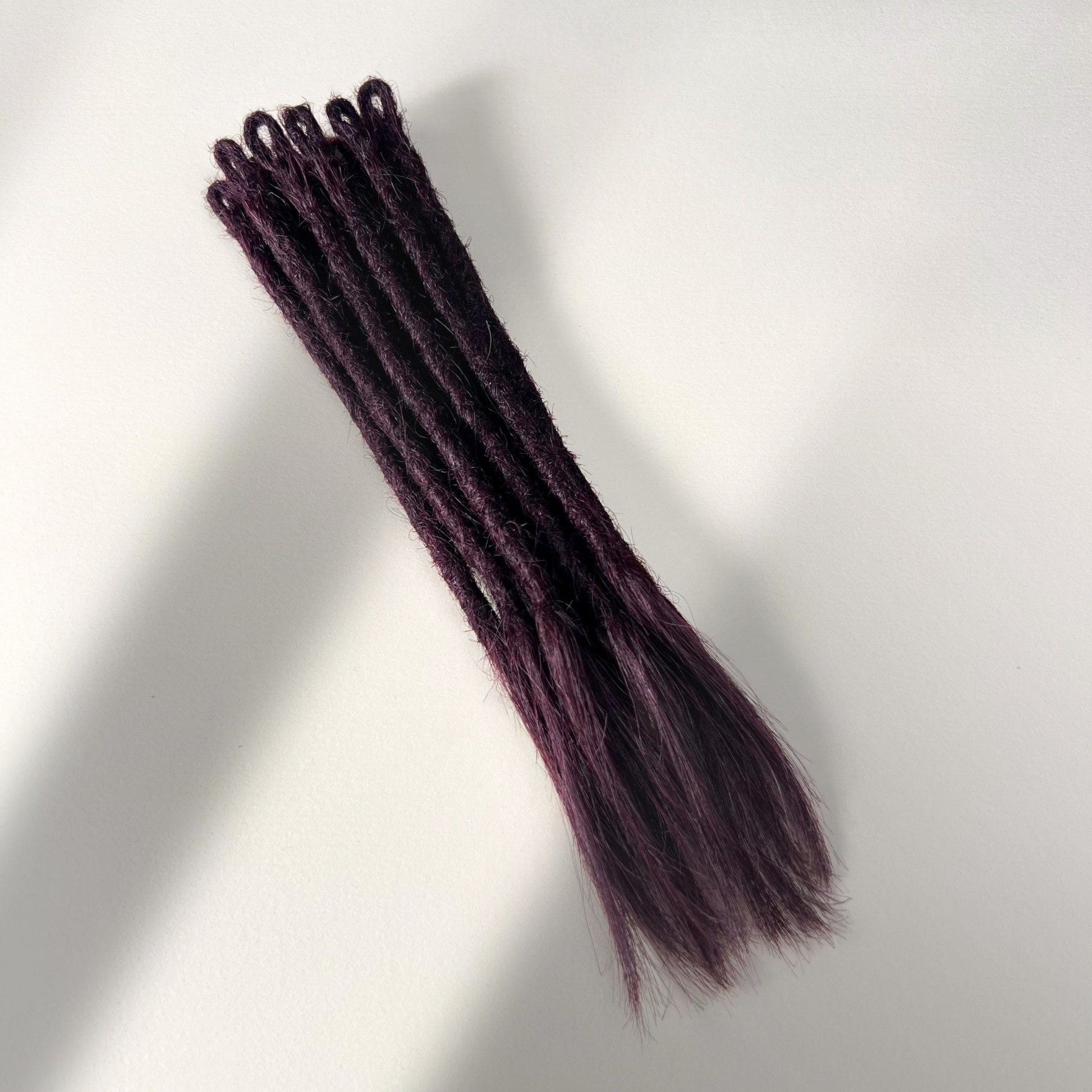 Full view of temporary single-ended straight loc extensions with open ends in Warm Marsala Red.