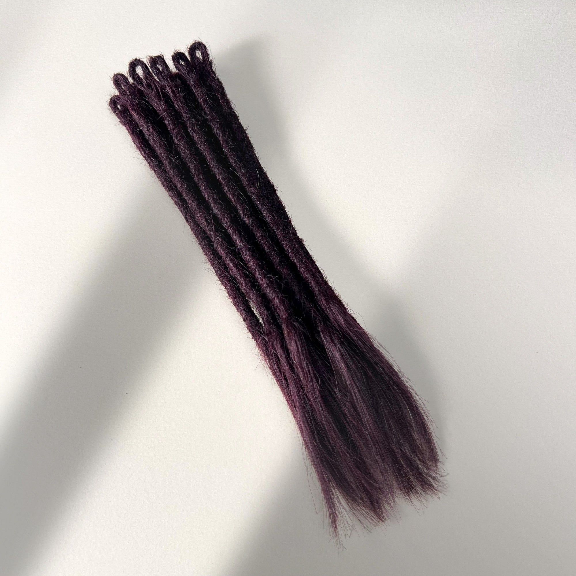 Full view of temporary single-ended straight loc extensions with open ends in Warm Marsala Red.