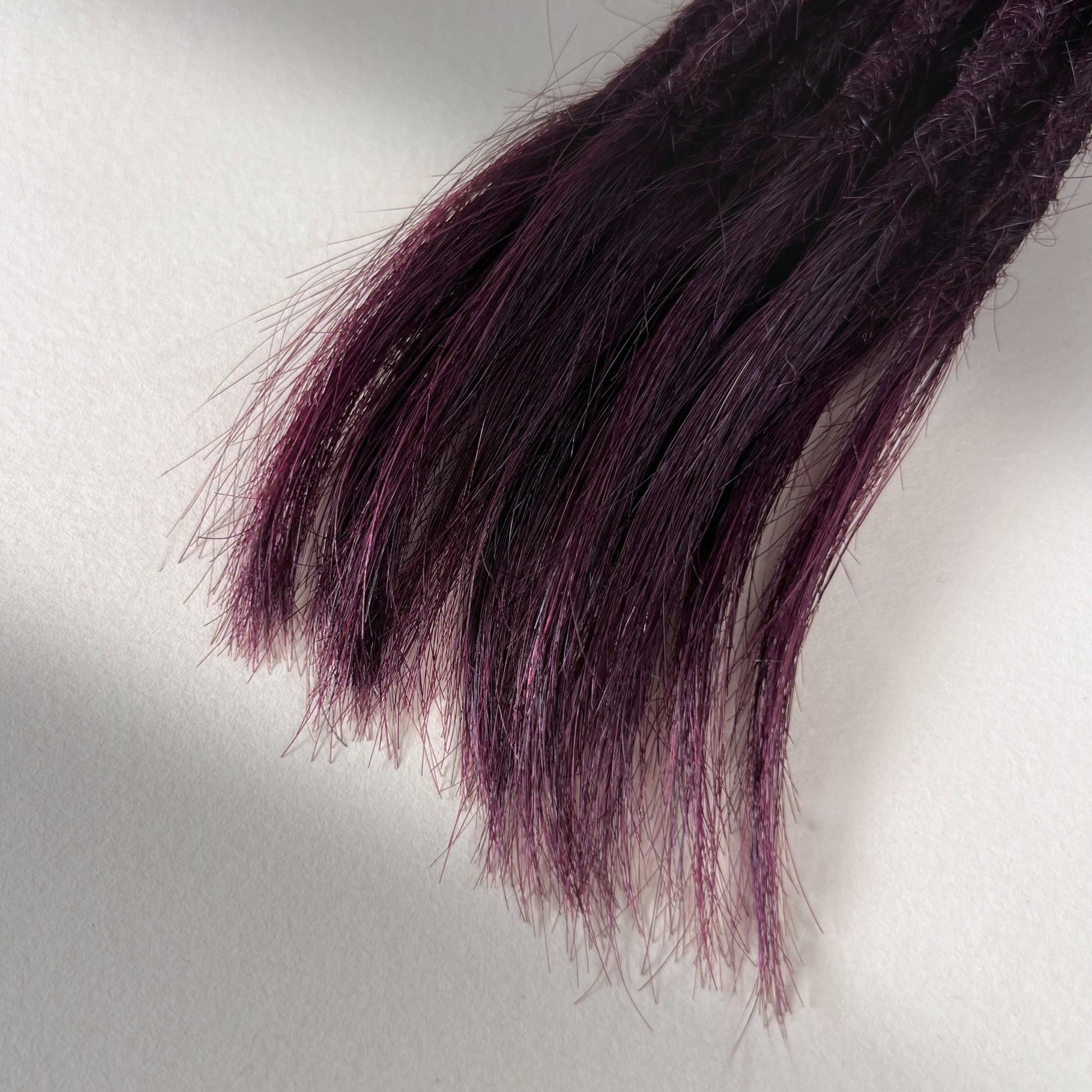 Tip detail of straight loc extensions with open ends in Warm Marsala Red.