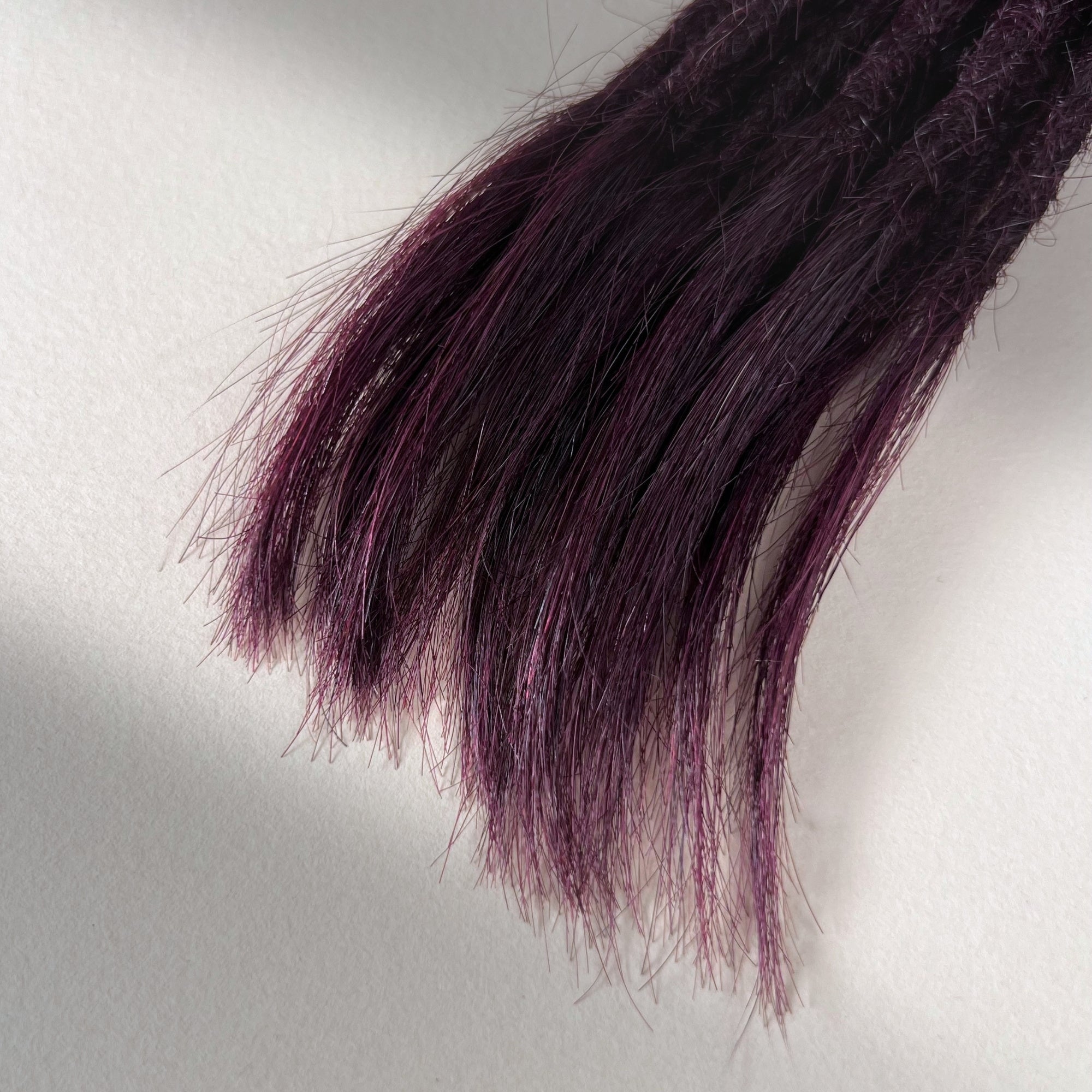 Tip detail of straight loc extensions with open ends in Warm Marsala Red.