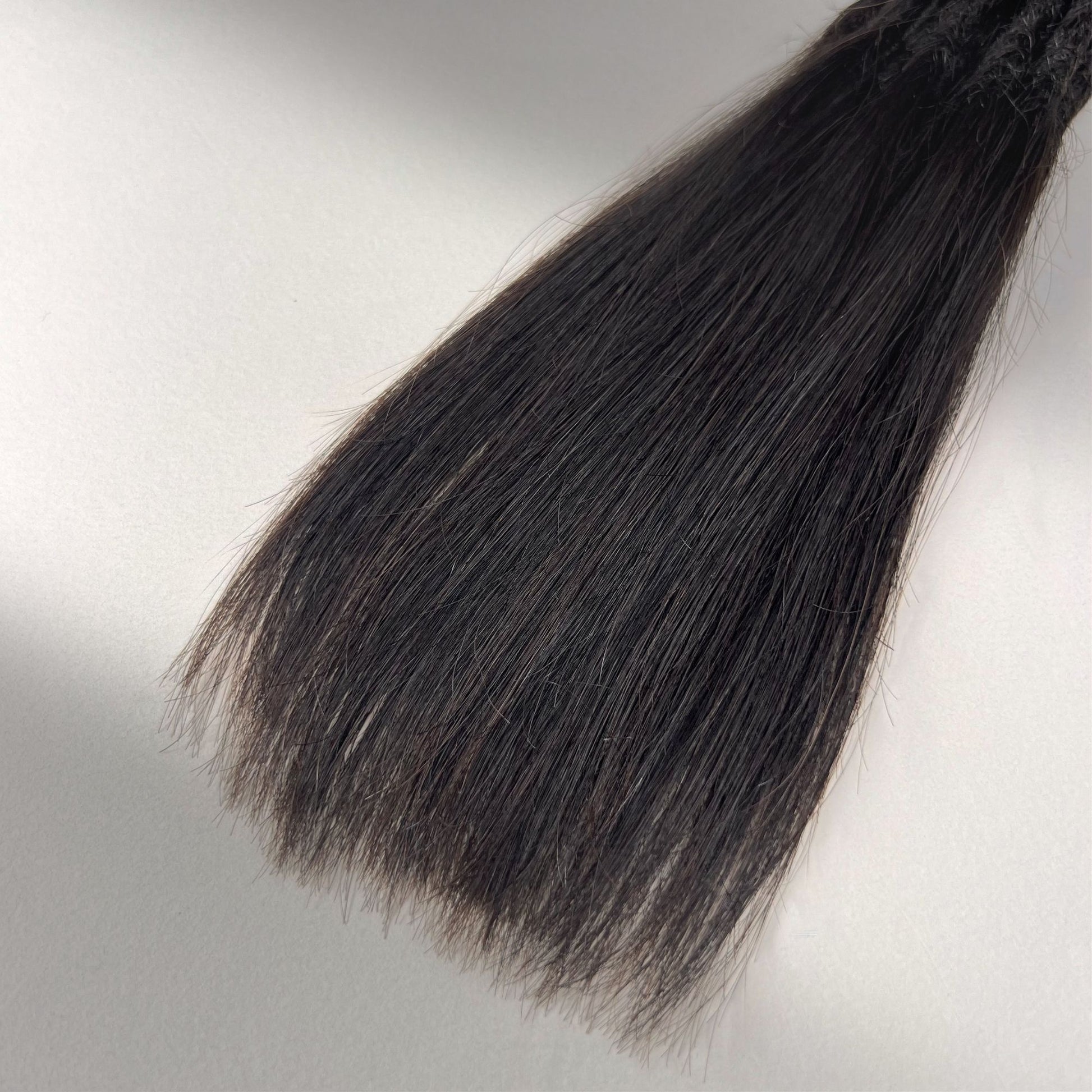 Tip detail of straight loc extensions with long loose ends in Deep Brown.