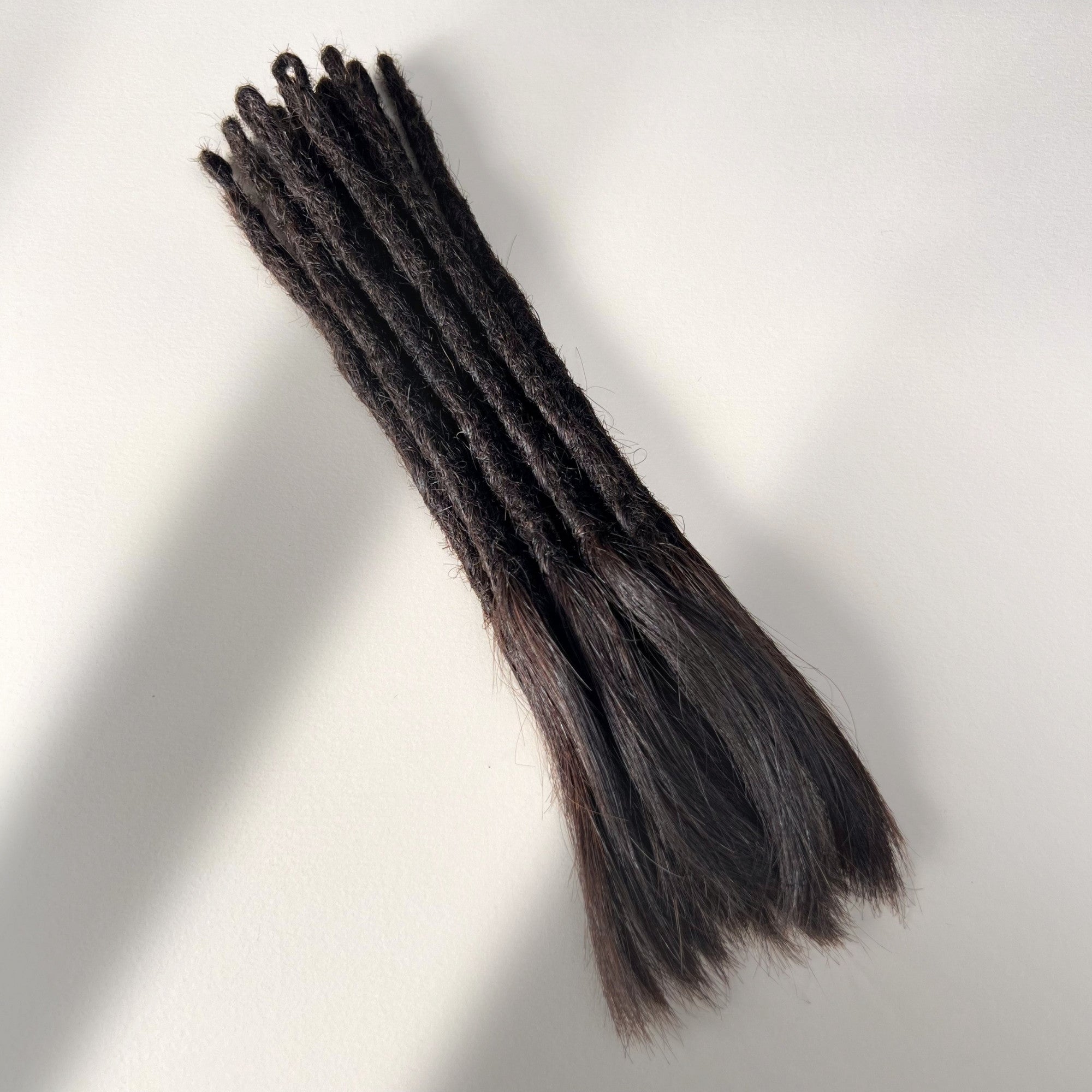 Full view of temporary single-ended straight loc extensions with open ends in Deep Brown.