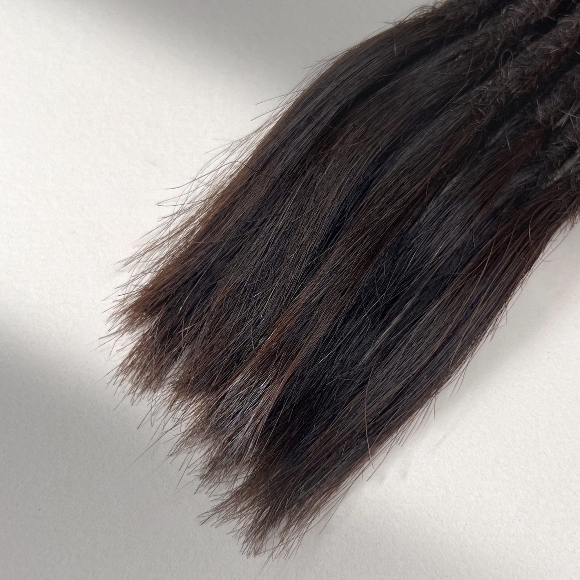 Tip detail of straight loc extensions with open ends in Deep Brown.
