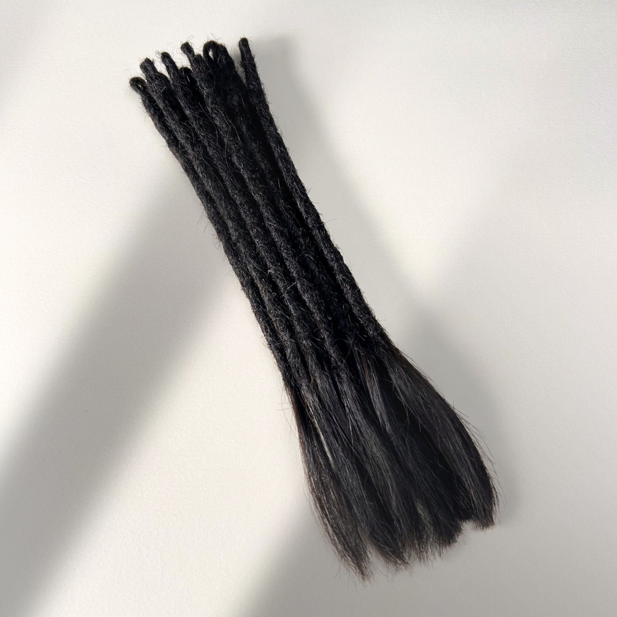 Full view of temporary single-ended straight loc extensions with open ends in Dark Ash Brown.