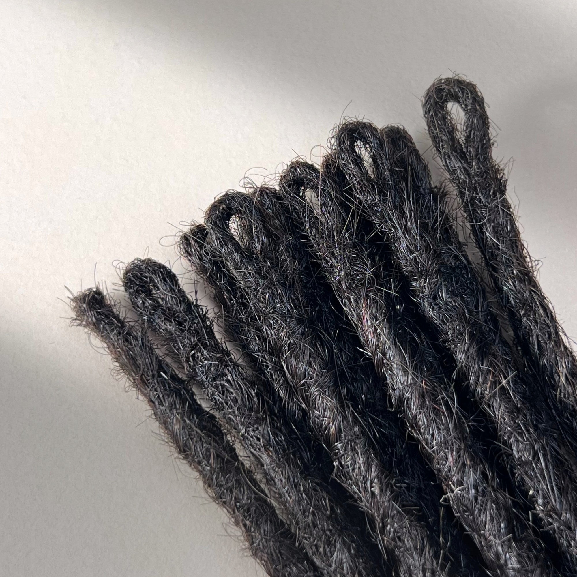 Loop detail of temporary single-ended straight loc extensions with open ends in Dark Ash Brown.