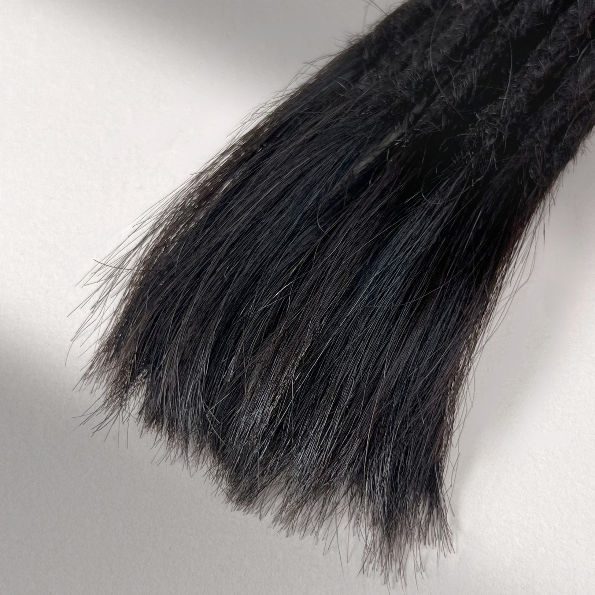 Tip detail of straight loc extensions with open ends in Dark Ash Brown.