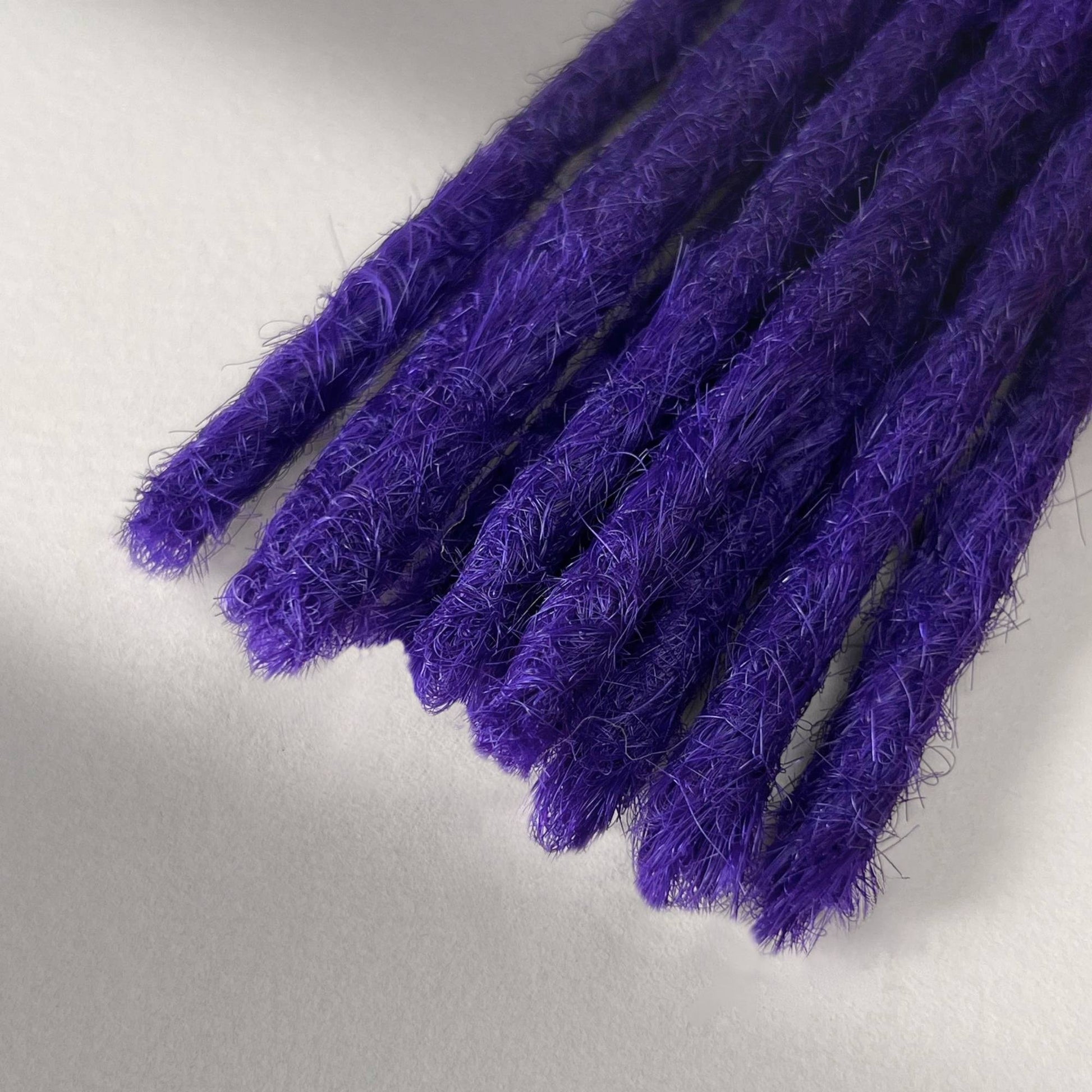 Tip detail of straight loc extensions with blunt ends in Orchid Violet.