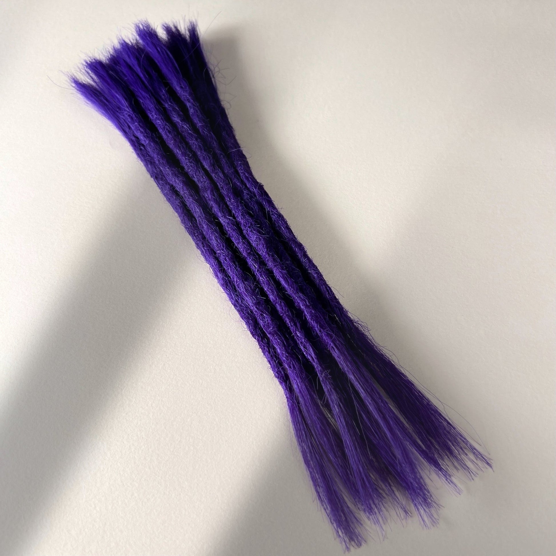 Full view of permanent straight loc extensions with open ends in Orchid Violet.